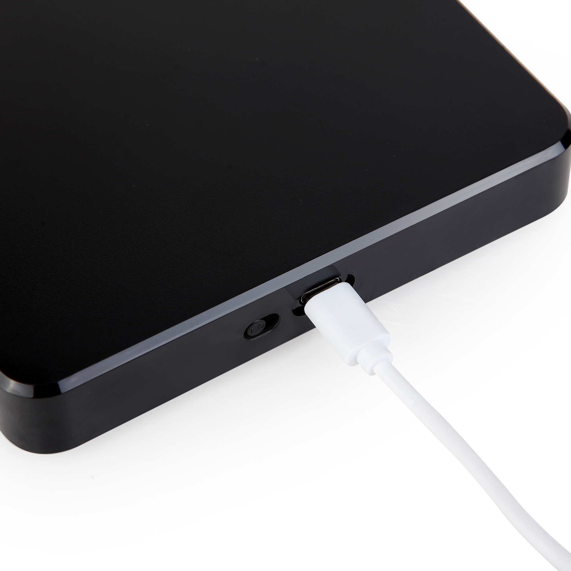 Zbliżenie czarnego urządzenia z wpiętym białym kablem ładującym.