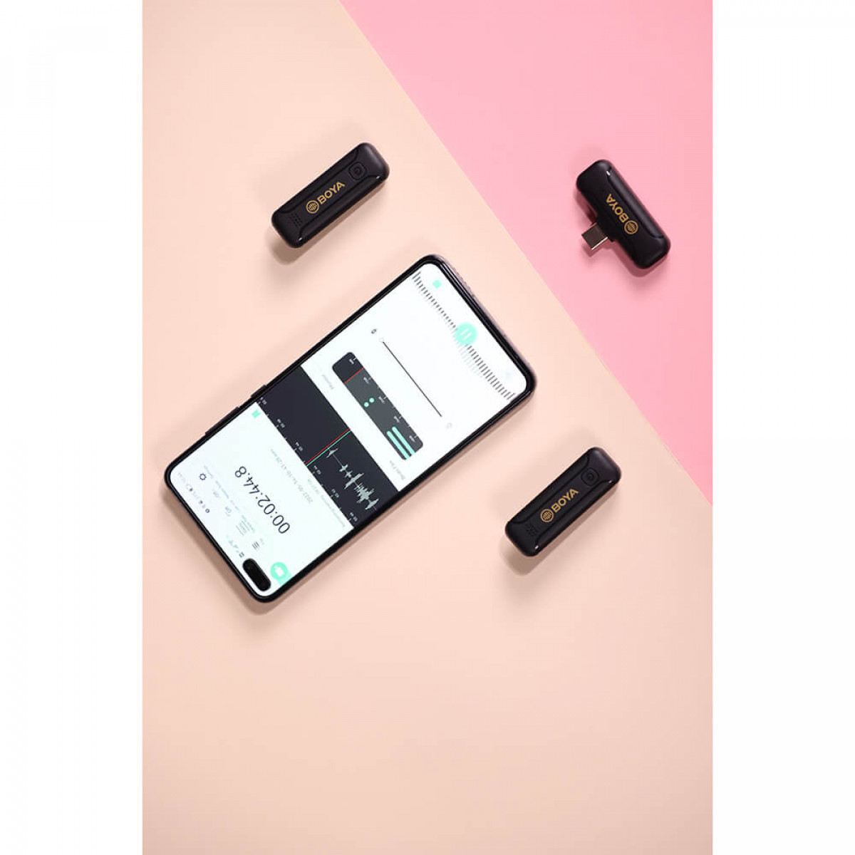 Un smartphone y tres micrófonos BOYA negros. El teléfono muestra gráficos de forma de onda de audio.