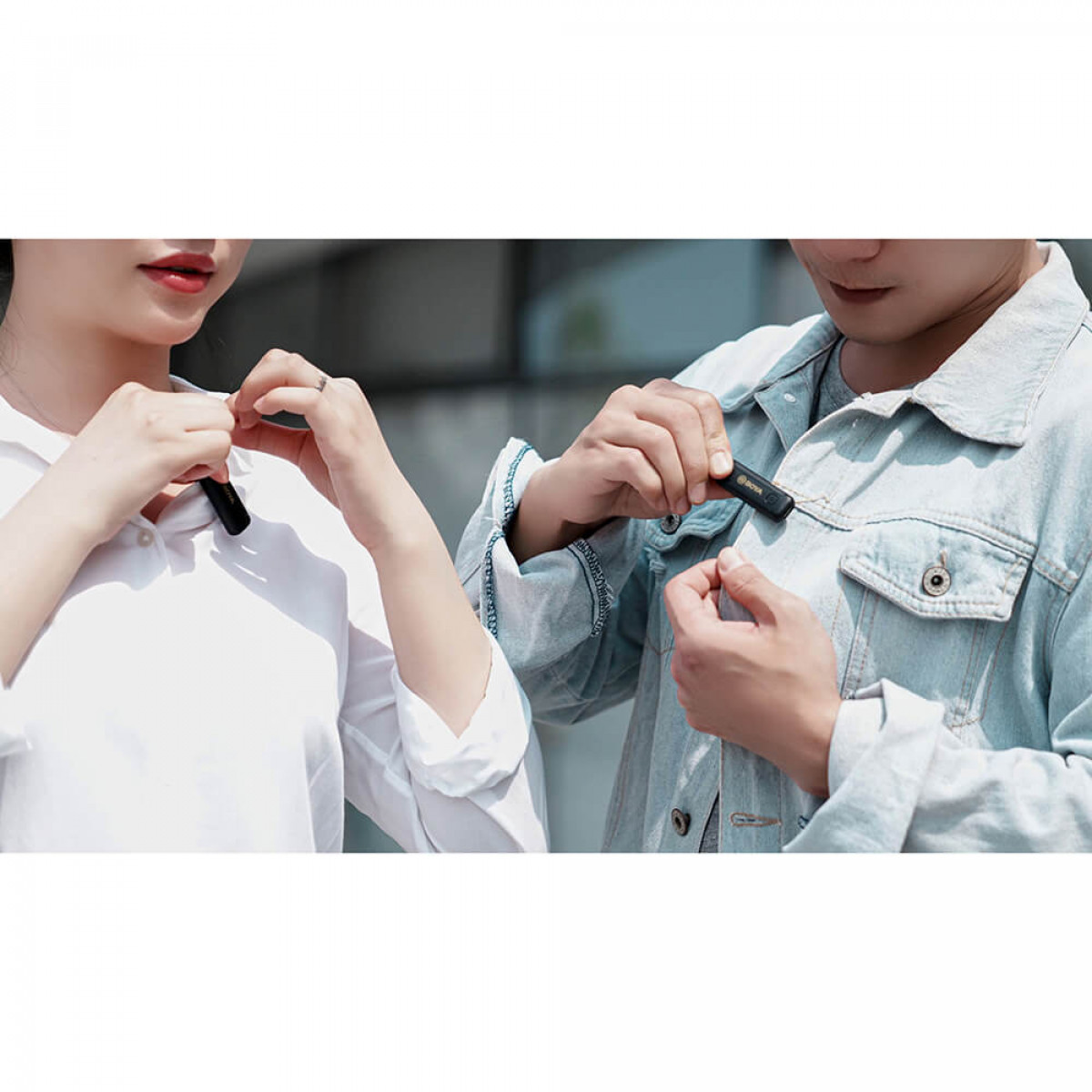 Dos personas colocándose pequeños micrófonos negros en la ropa. Llevan camisas claras.