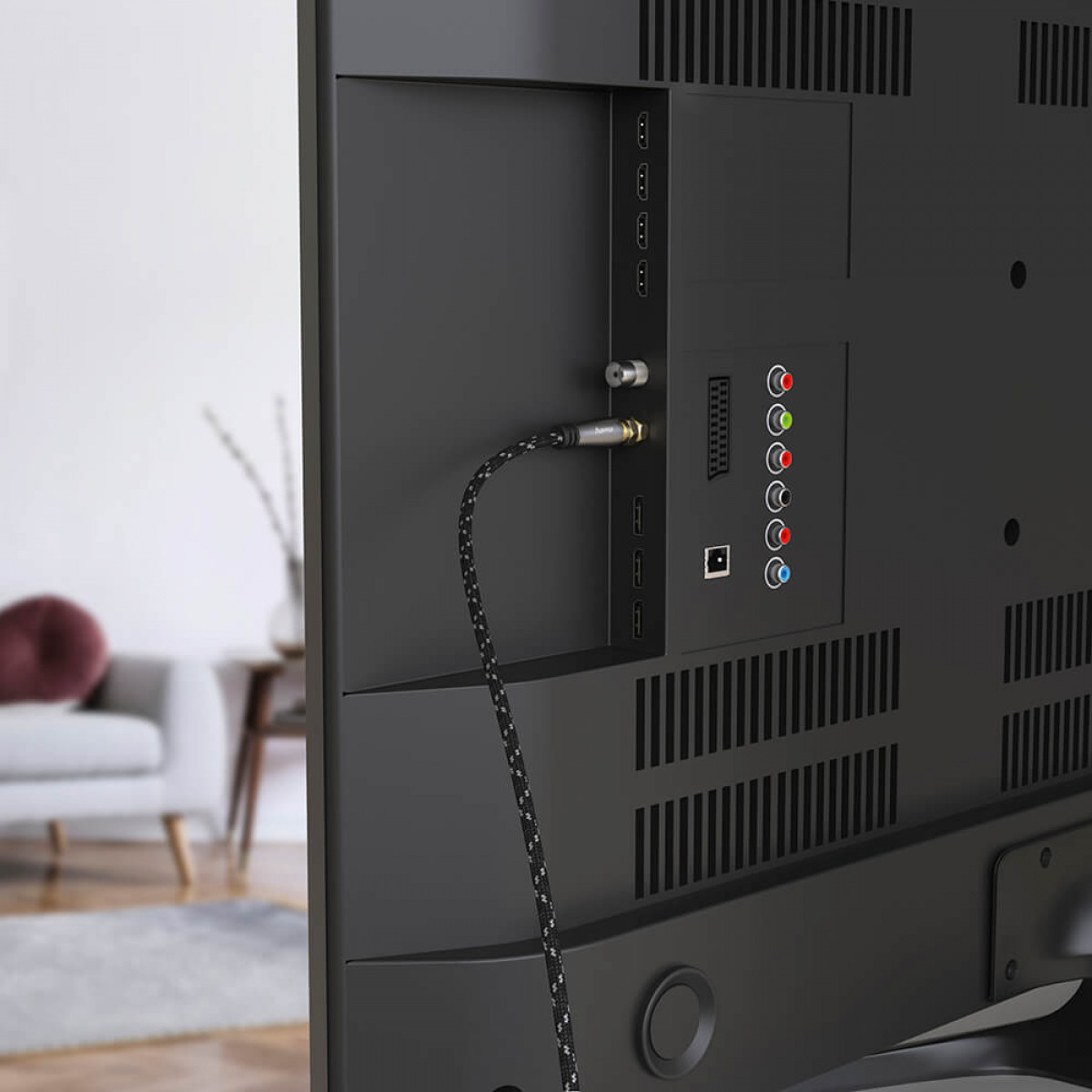Tył telewizora z podłączonym kablem. Widoczne porty, kabel ma czarno-biały wzór.