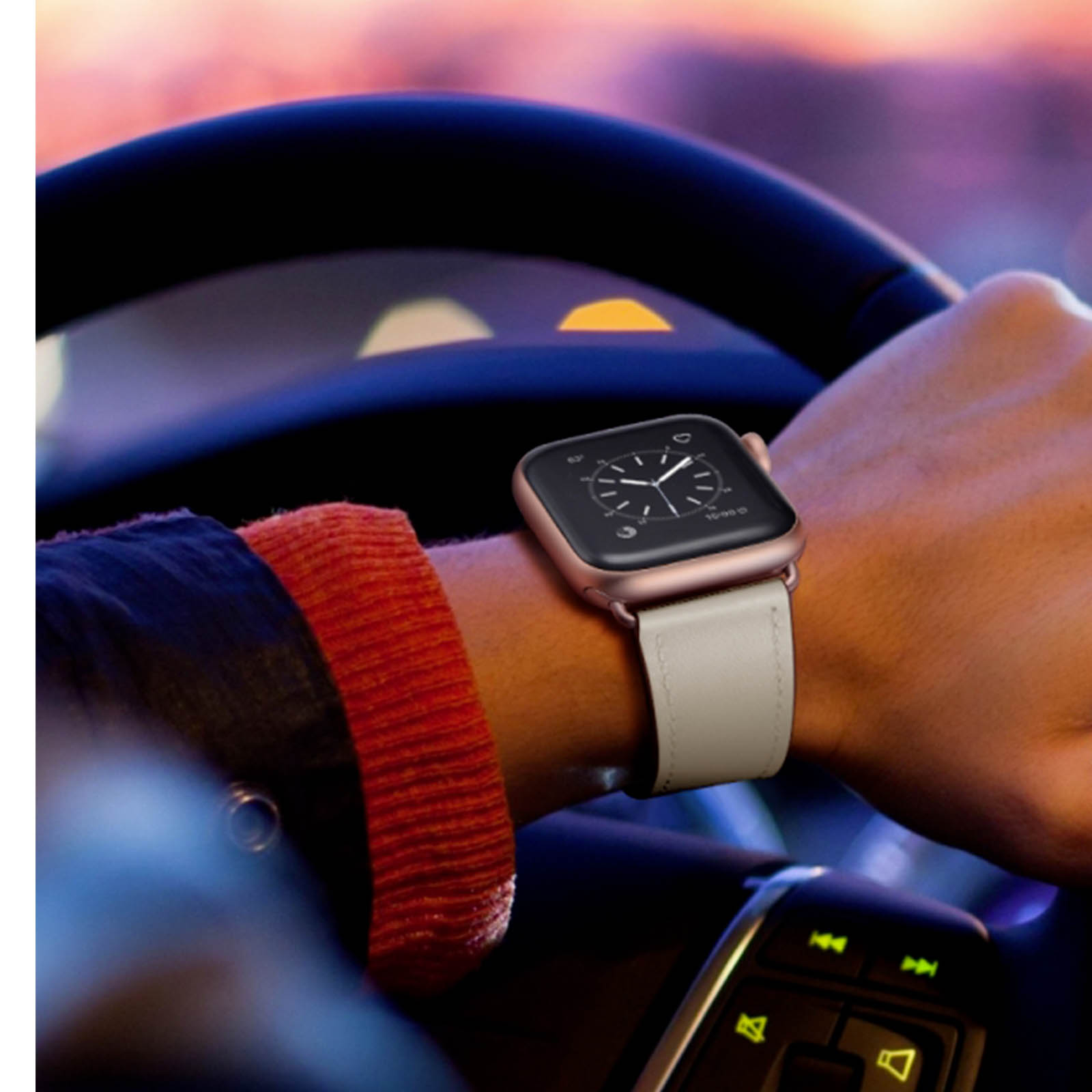 Una persona che indossa uno smartwatch mentre guida. L'orologio ha un cinturino bianco e il volante è visibile.