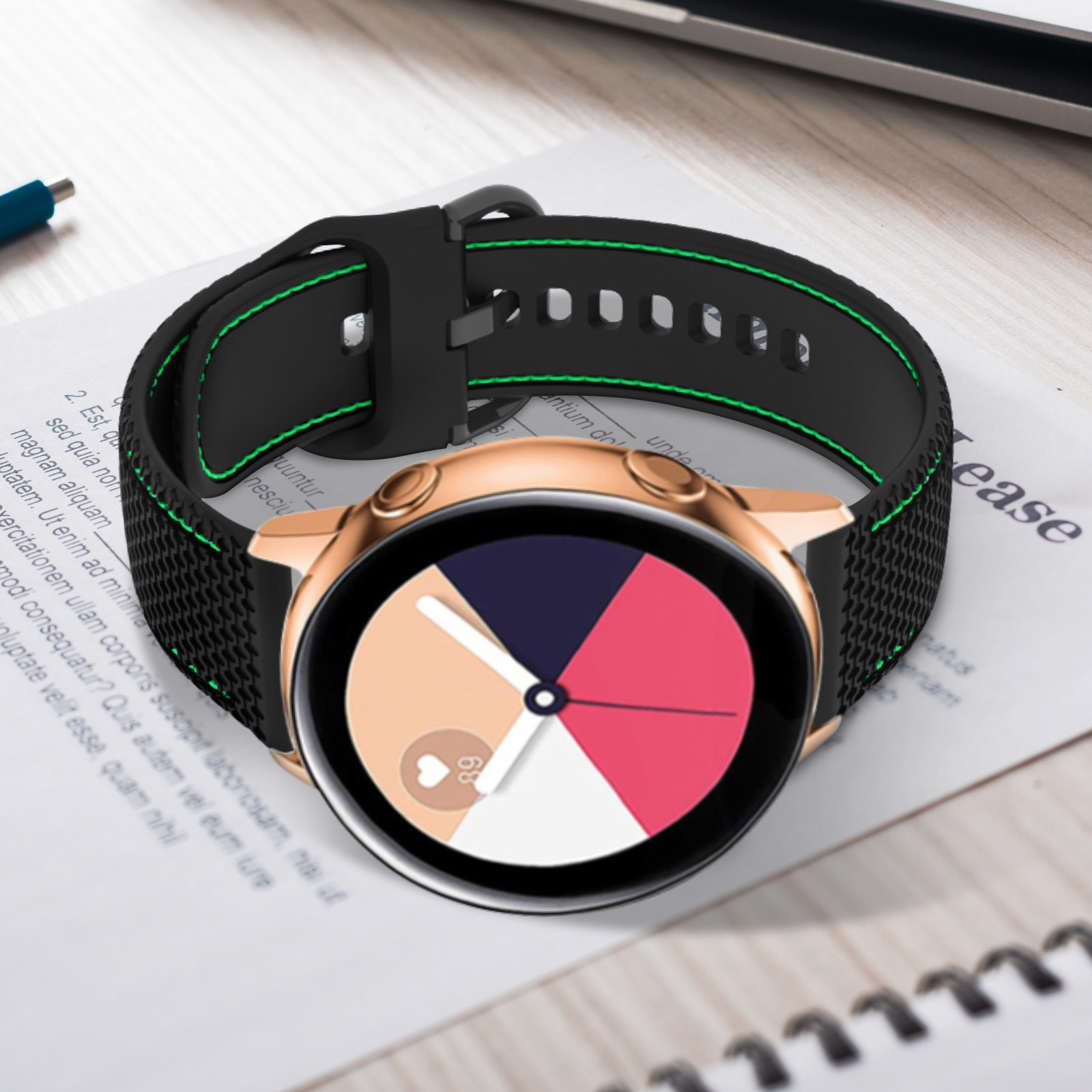 Un reloj inteligente oro rosa con correa negra y verde sobre papel con texto.