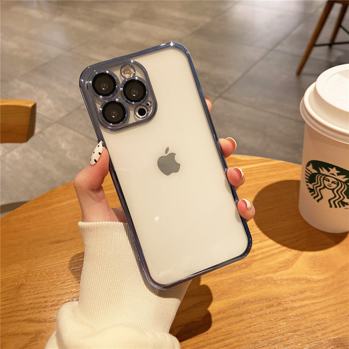Hand, die eine klare Handyhülle mit einem Telefon darin hält, mit weißem Hintergrund und Holztisch.