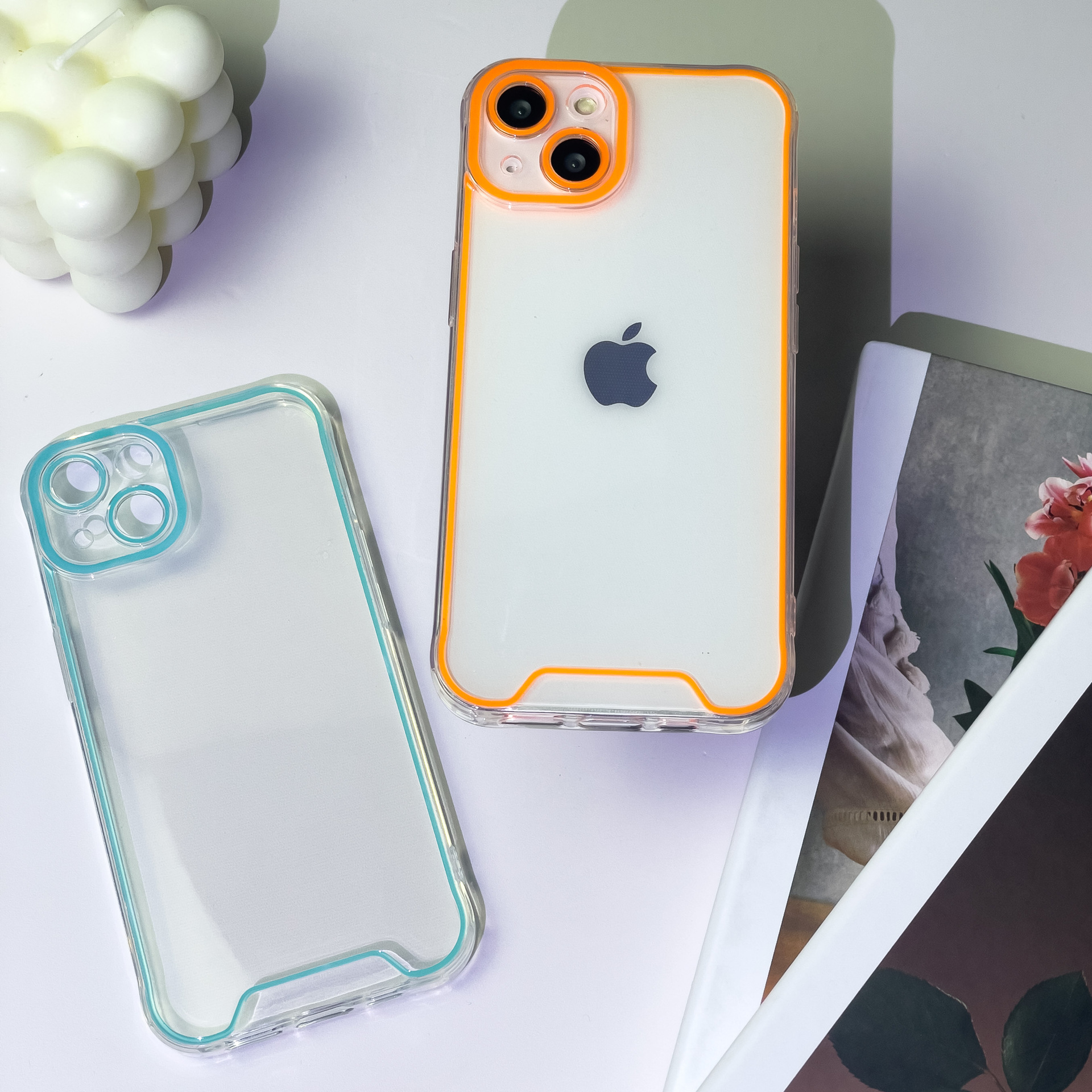 Zwei Handyhüllen auf weißer Oberfläche. Eine ist transparent, die andere weiß mit orangen Details.