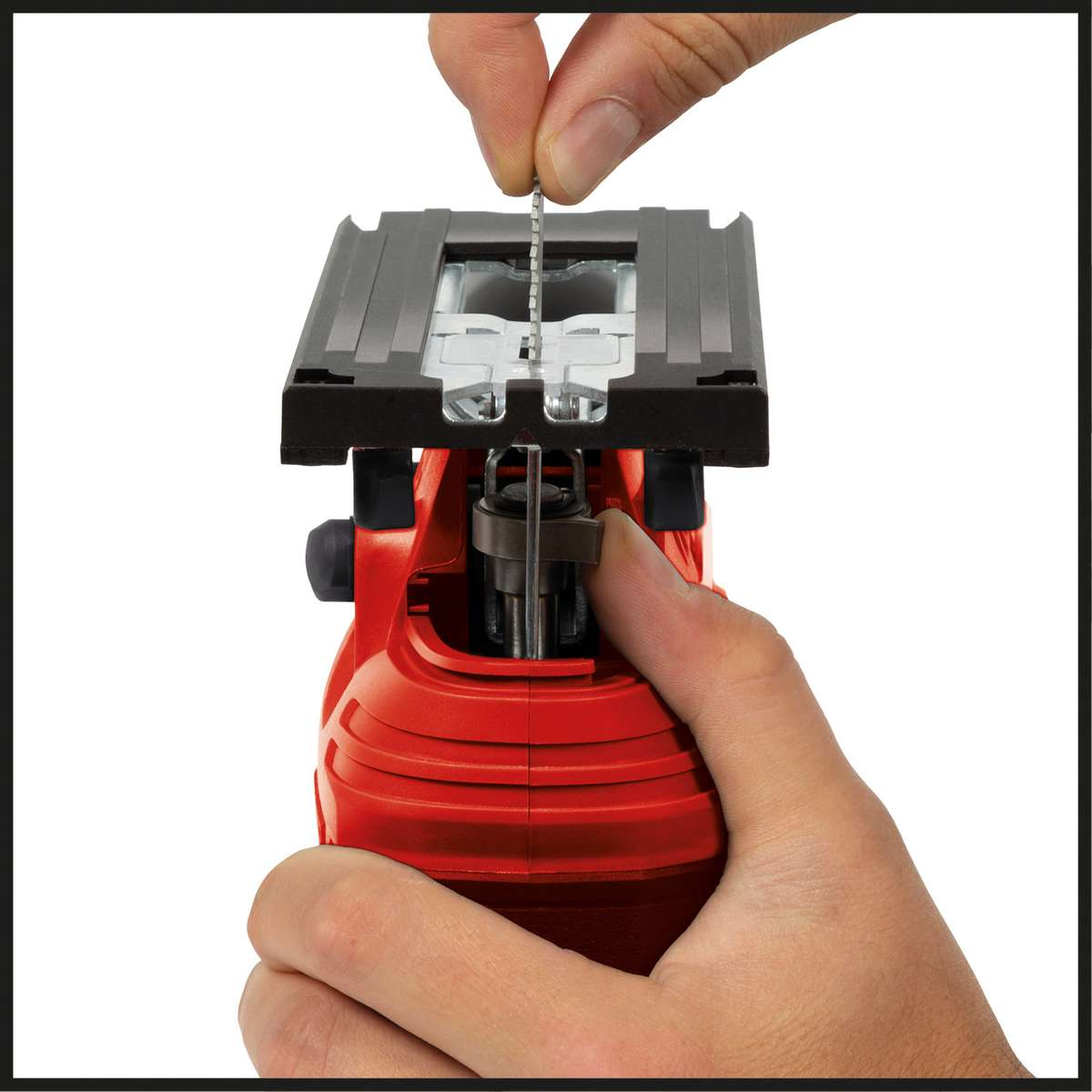 Die Hand einer Person setzt ein Stichsägeblatt in eine rot-schwarze elektrische Stichsägemaschine ein.