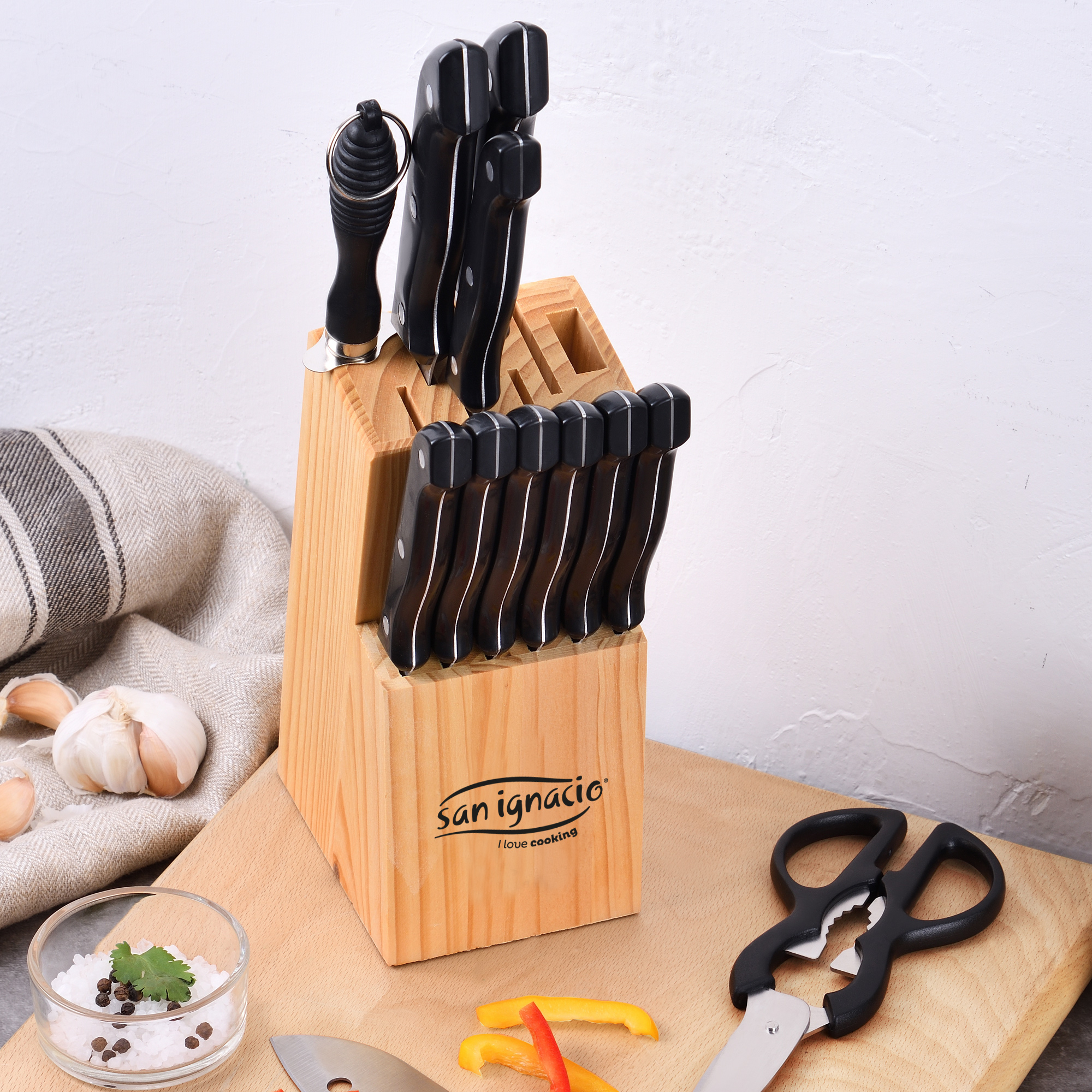 Bloque de cuchillos con cuchillos negros. Varios cuchillos y tijeras en una tabla de madera.
