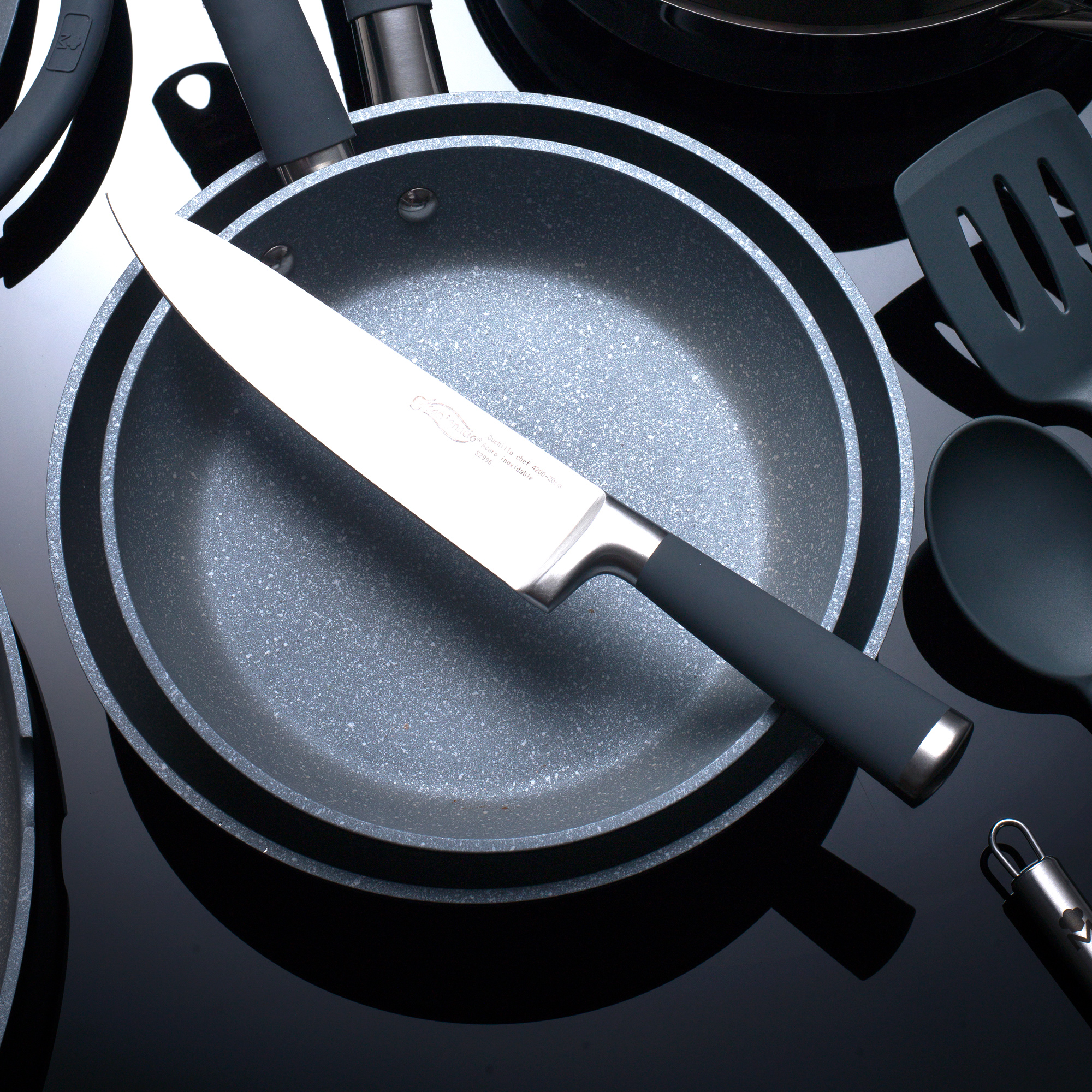 Un cuchillo está en una sartén gris. Otras herramientas de cocina están alrededor.