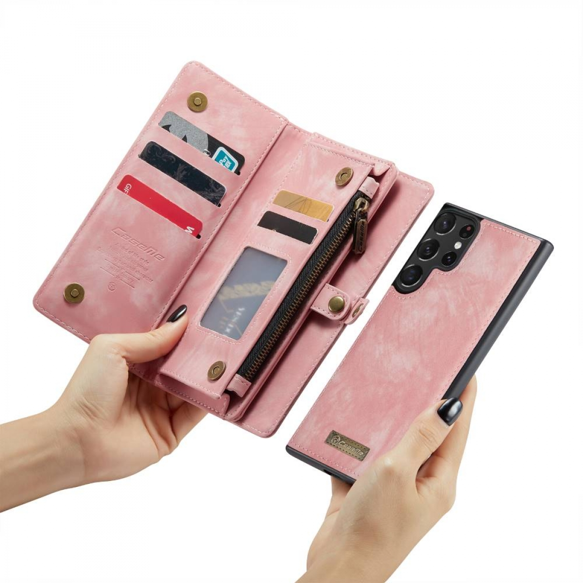 Eine rosa Handyhülle geöffnet, zeigt Karten, Bargeld und ein Telefon. Wird in zwei Händen gehalten.