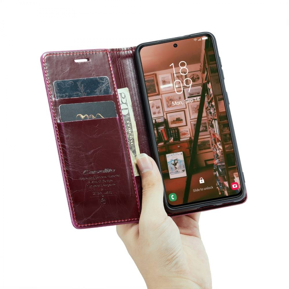 Eine Hand hält ein Telefon in einer roten Leder-Brieftaschen-Hülle. Der Bildschirm zeigt ein Zimmer.