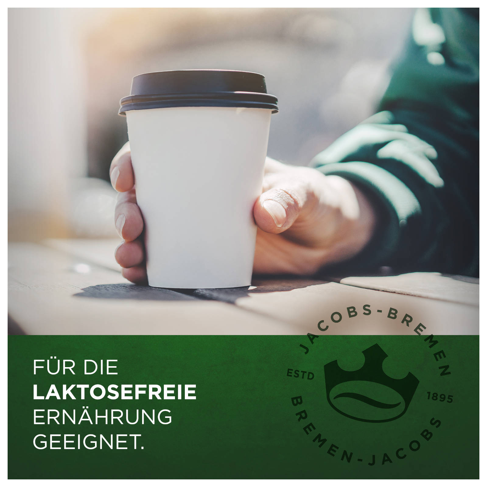 Die Hand einer Person, die eine weiße Kaffeetasse mit braunem Deckel hält, grüner Hintergrund.