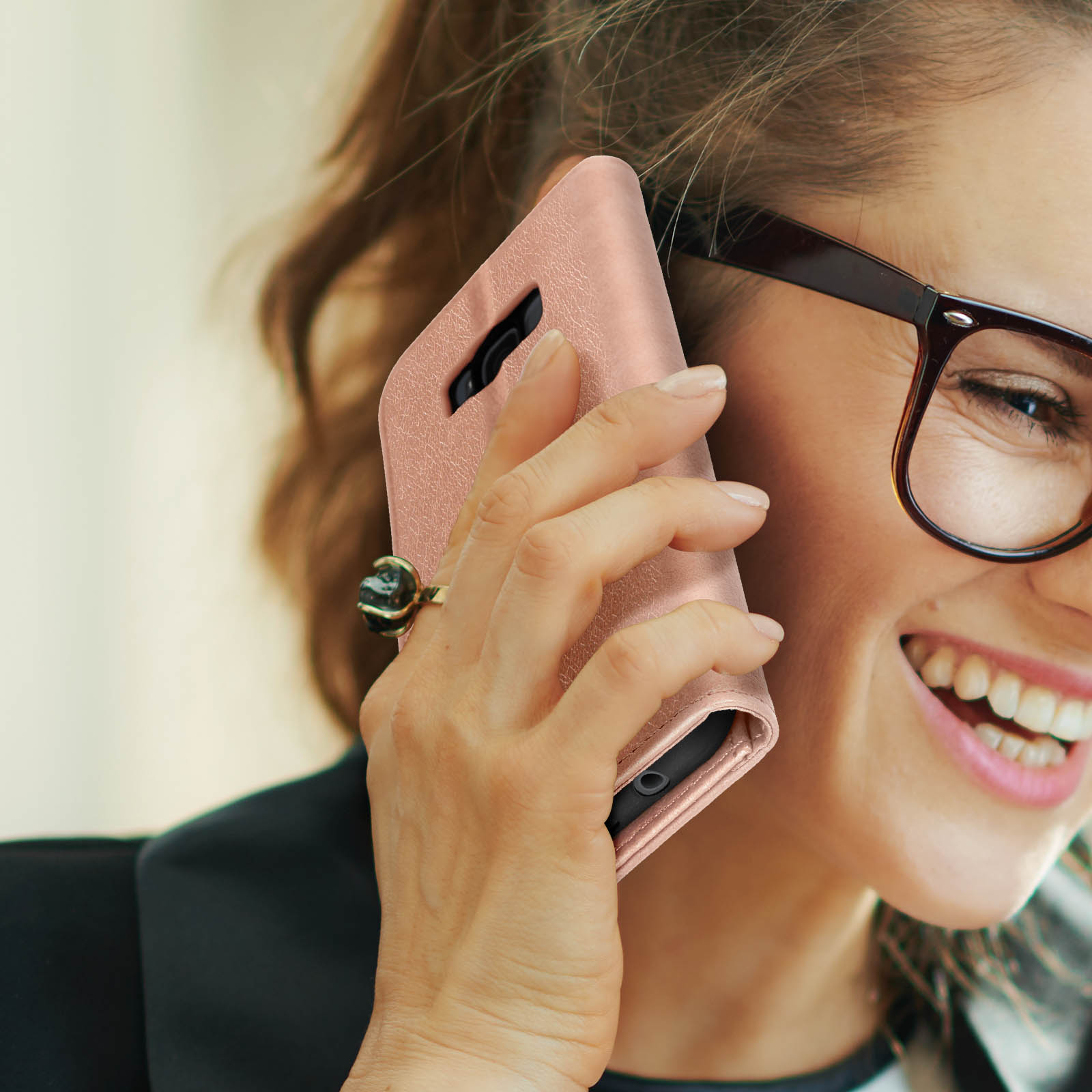 Vrouw die belt op een roségouden telefoon, met bril en ring.