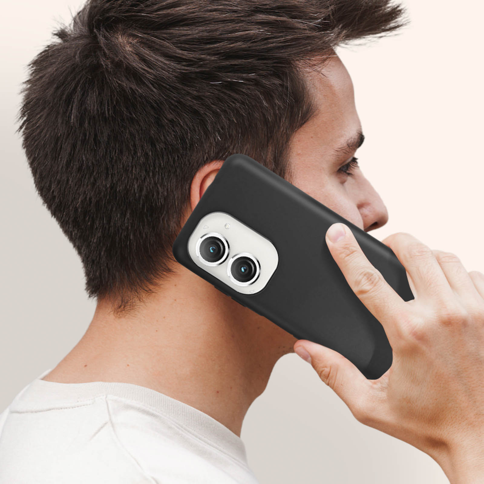 Un uomo tiene un telefono nero all'orecchio, mostrando gli obiettivi della fotocamera.