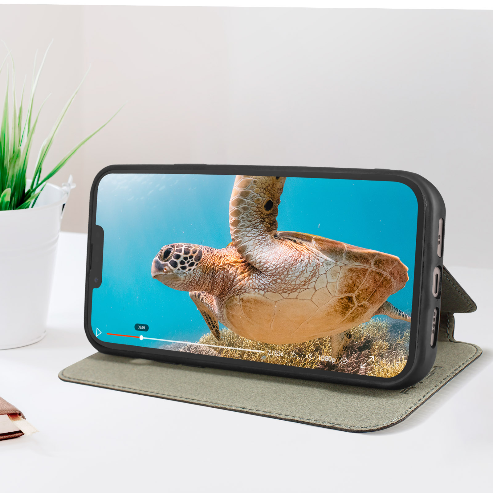 Téléphone dans un étui lisant une vidéo d'une tortue de mer. L'étui est ouvert et sur une table.