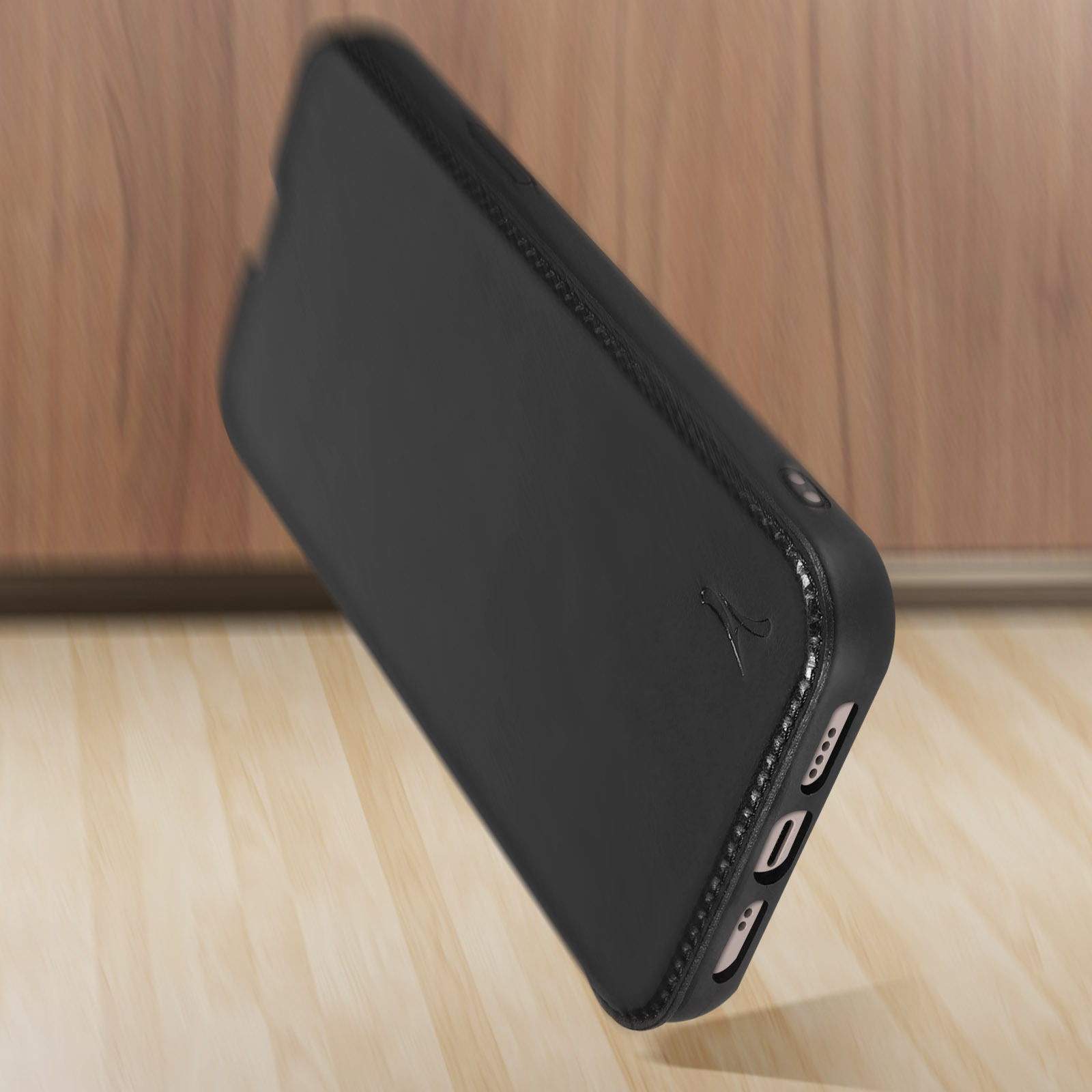 Coque de téléphone noire sur une surface en bois. La coque a un dos texturé et un port de charge visible.