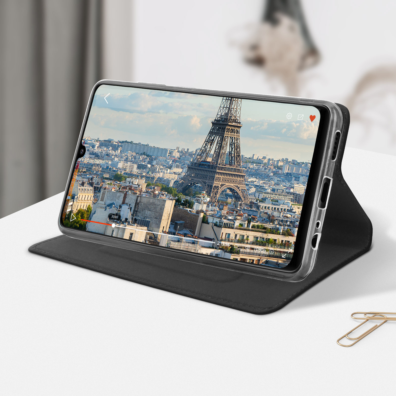 Tablet con un video in riproduzione, custodia. Lo sfondo è un paesaggio urbano con la Torre Eiffel.