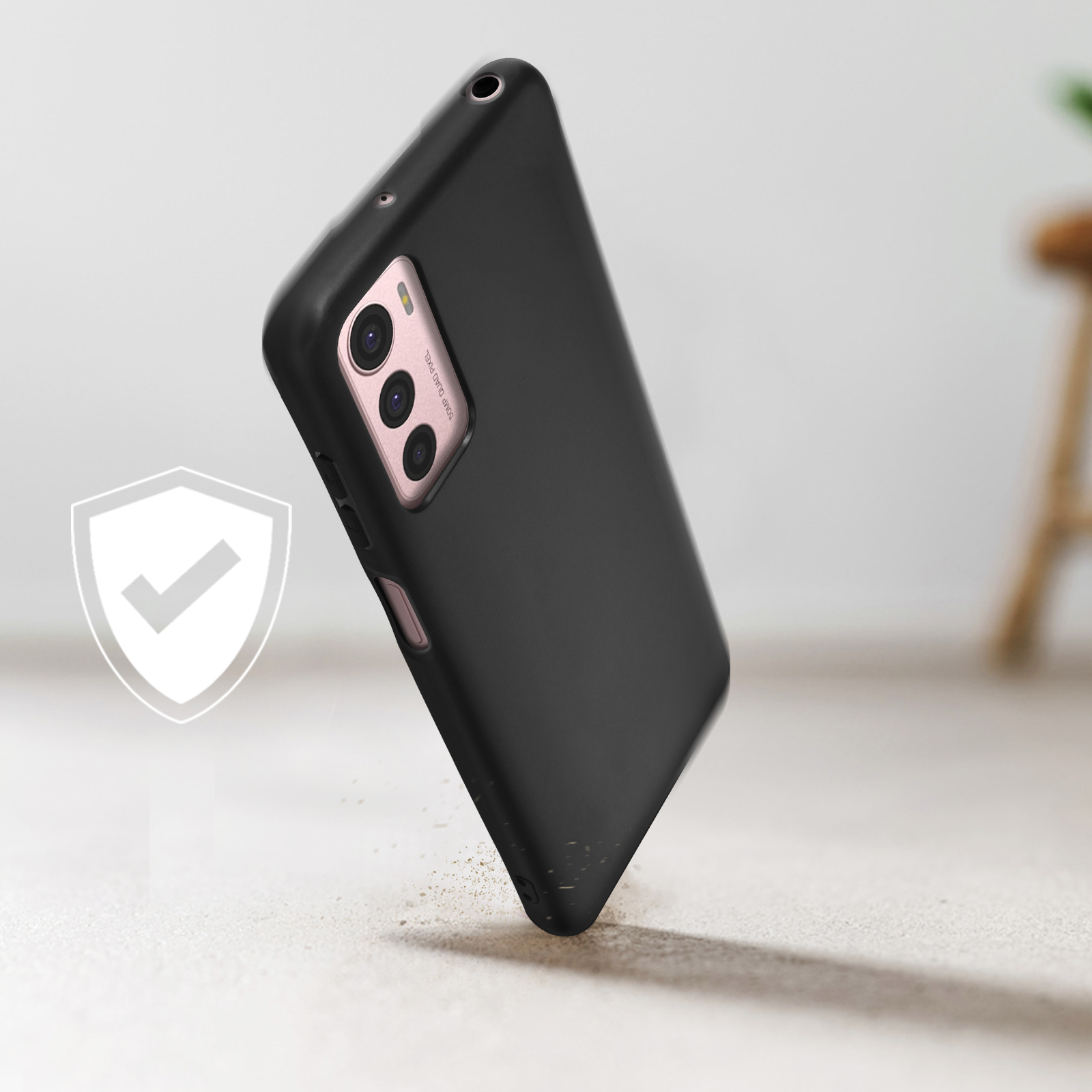 Custodia nera per telefono con modulo fotocamera rosa, inclinata e fluttuante vicino a un'icona di scudo.