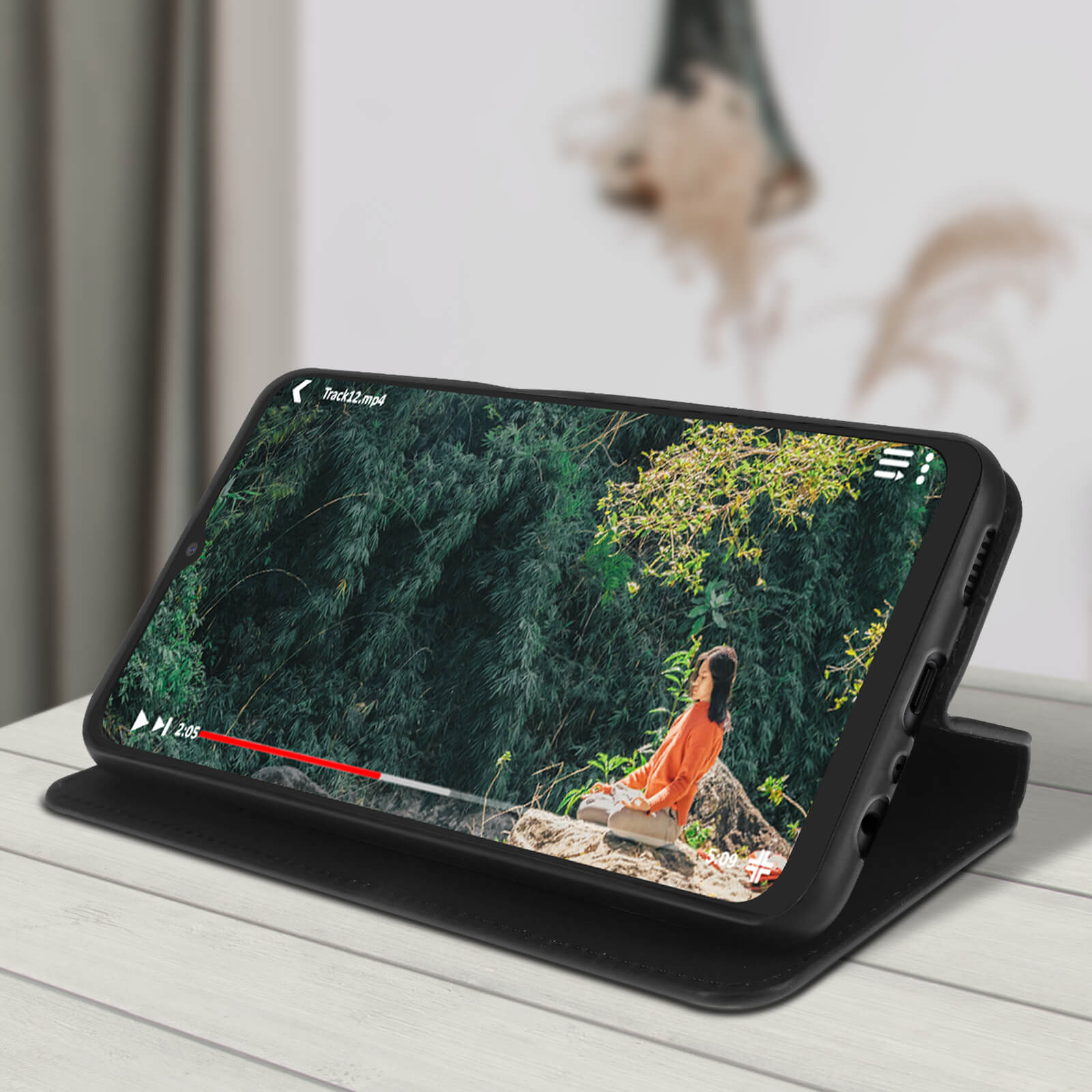 Telefono in una custodia nera che mostra un video di una donna nella natura.