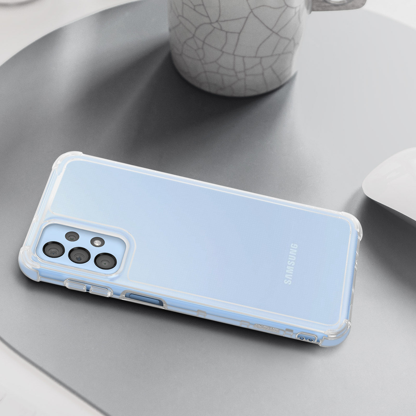 Funda transparente para teléfono sobre una superficie azul claro. Taza y ratón en el fondo.