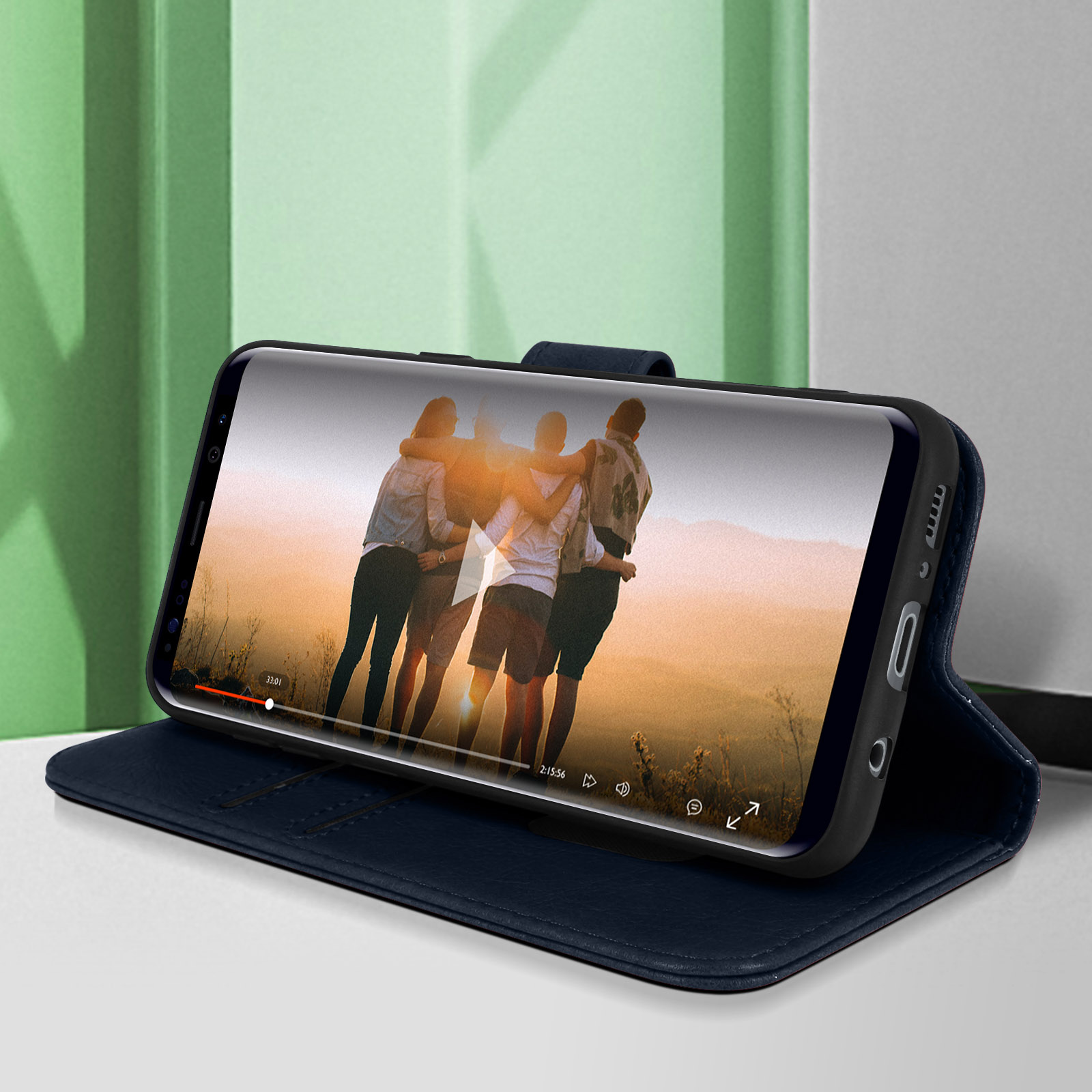 Funda de teléfono abierta con un video en reproducción. Funda azul, personas en pantalla. Fondo verde.
