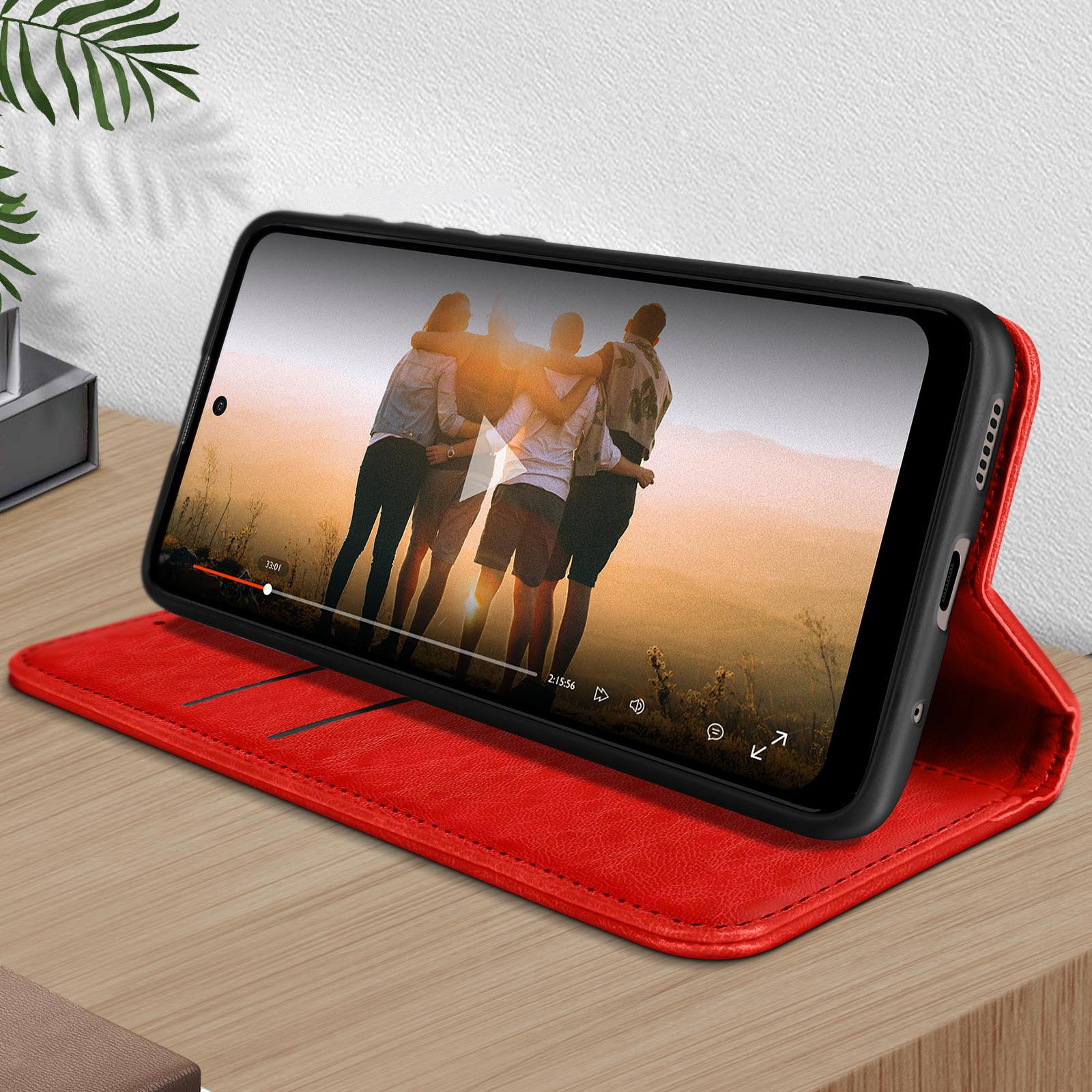 Ein Smartphone mit roter Hülle, das ein Video von sich umarmenden Menschen zeigt.