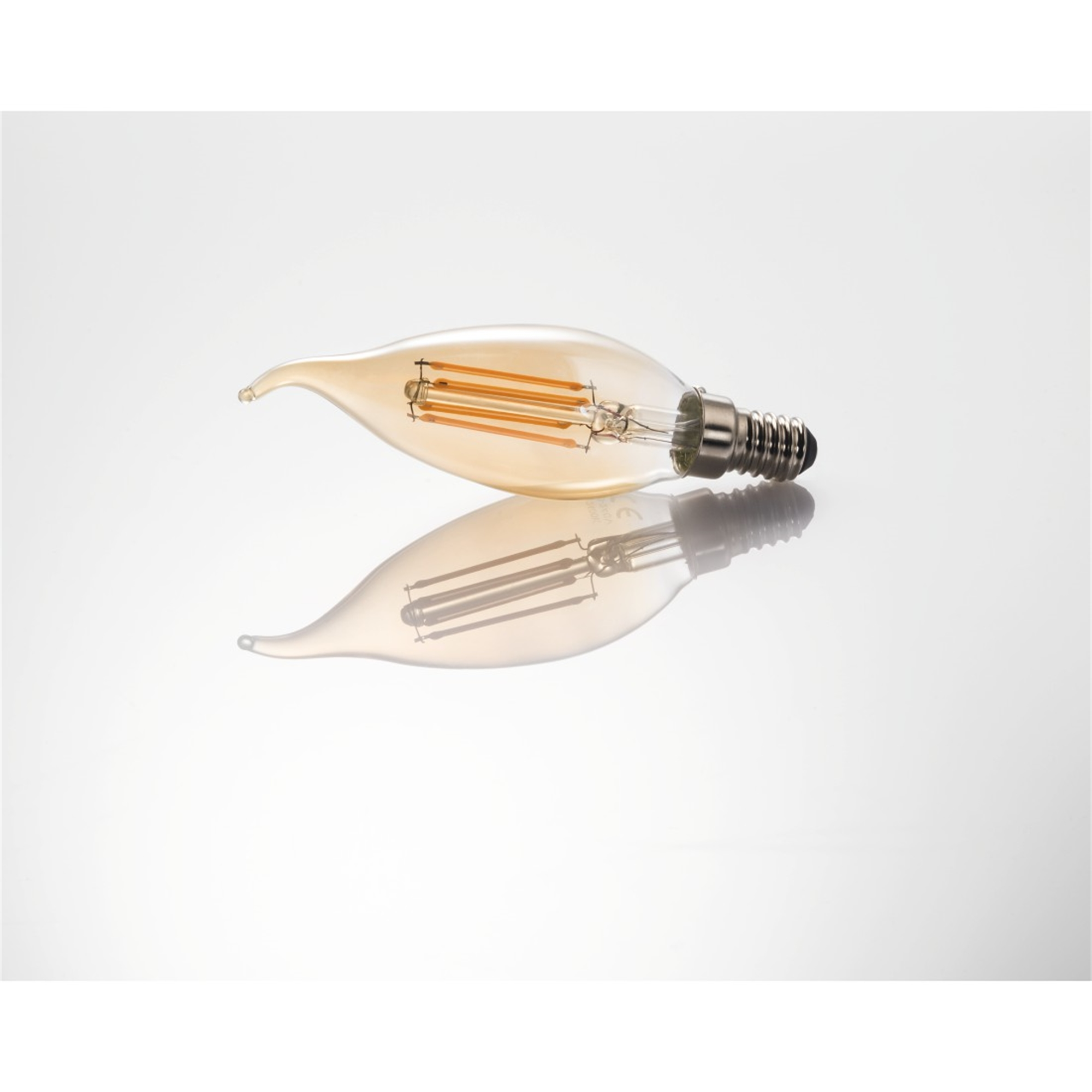 Une ampoule en forme de flamme, posée sur une surface blanche réfléchissante.