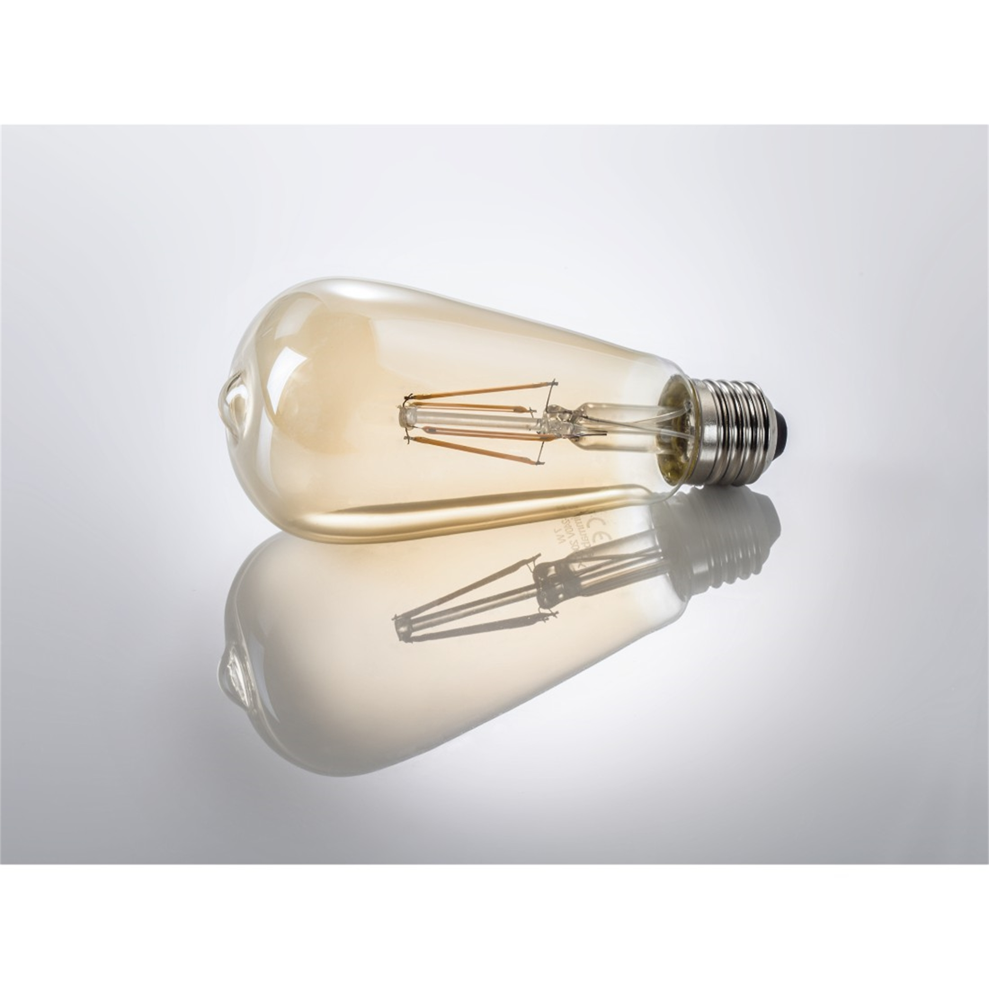 Lampadina color beige con filamenti visibili, su superficie riflettente; ombra.