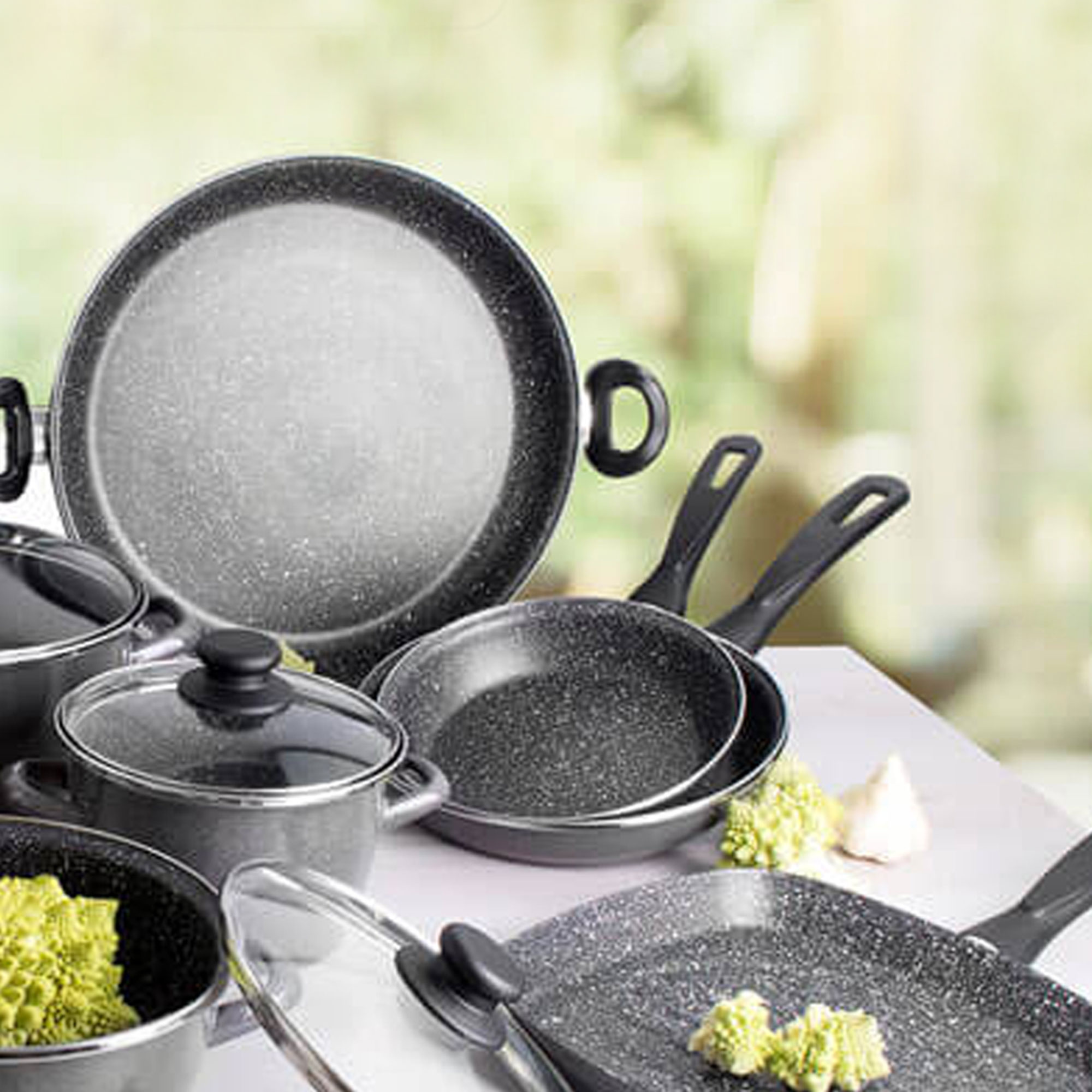 Juego de cocina con sartenes y ollas. Las sartenes y ollas son de color gris oscuro con una textura moteada.