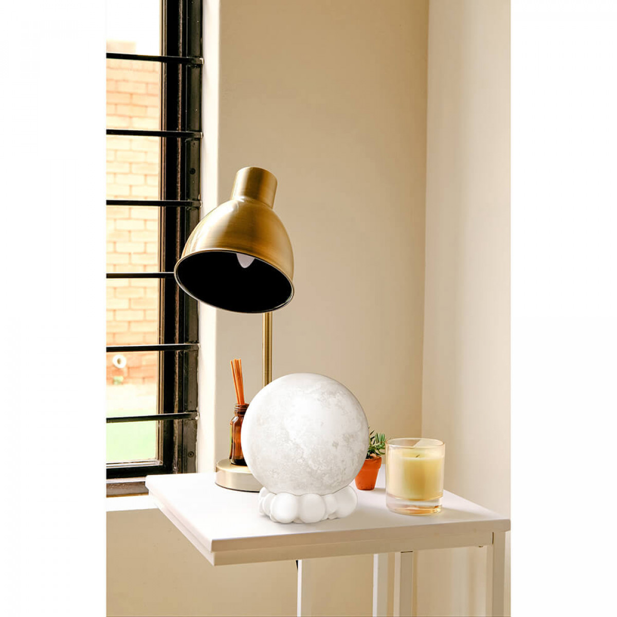 Ein weißer Tisch mit Lampe, mondförmigem Licht und Kerze.