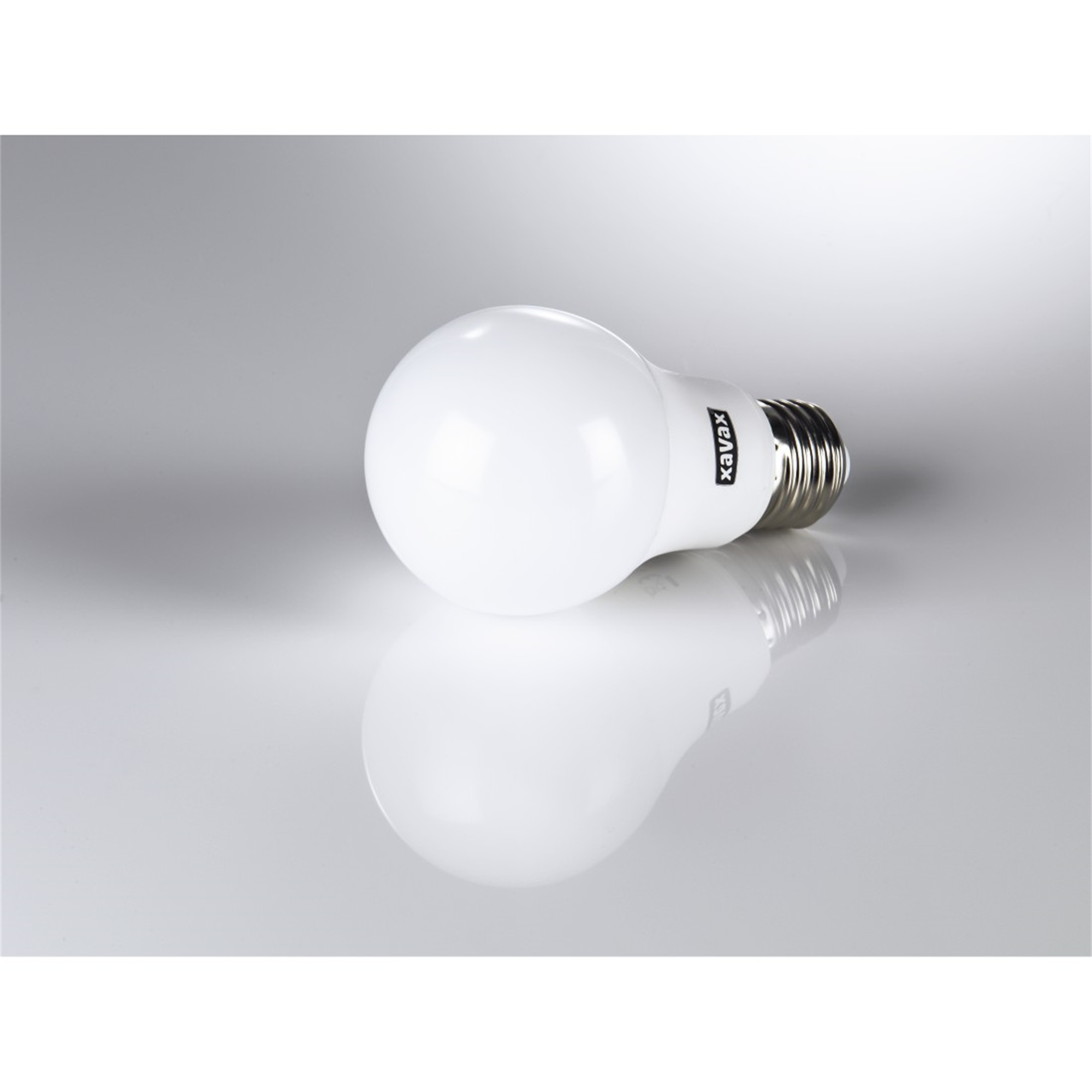 Une ampoule blanche avec une base argentée, se reflétant sur une surface blanche.