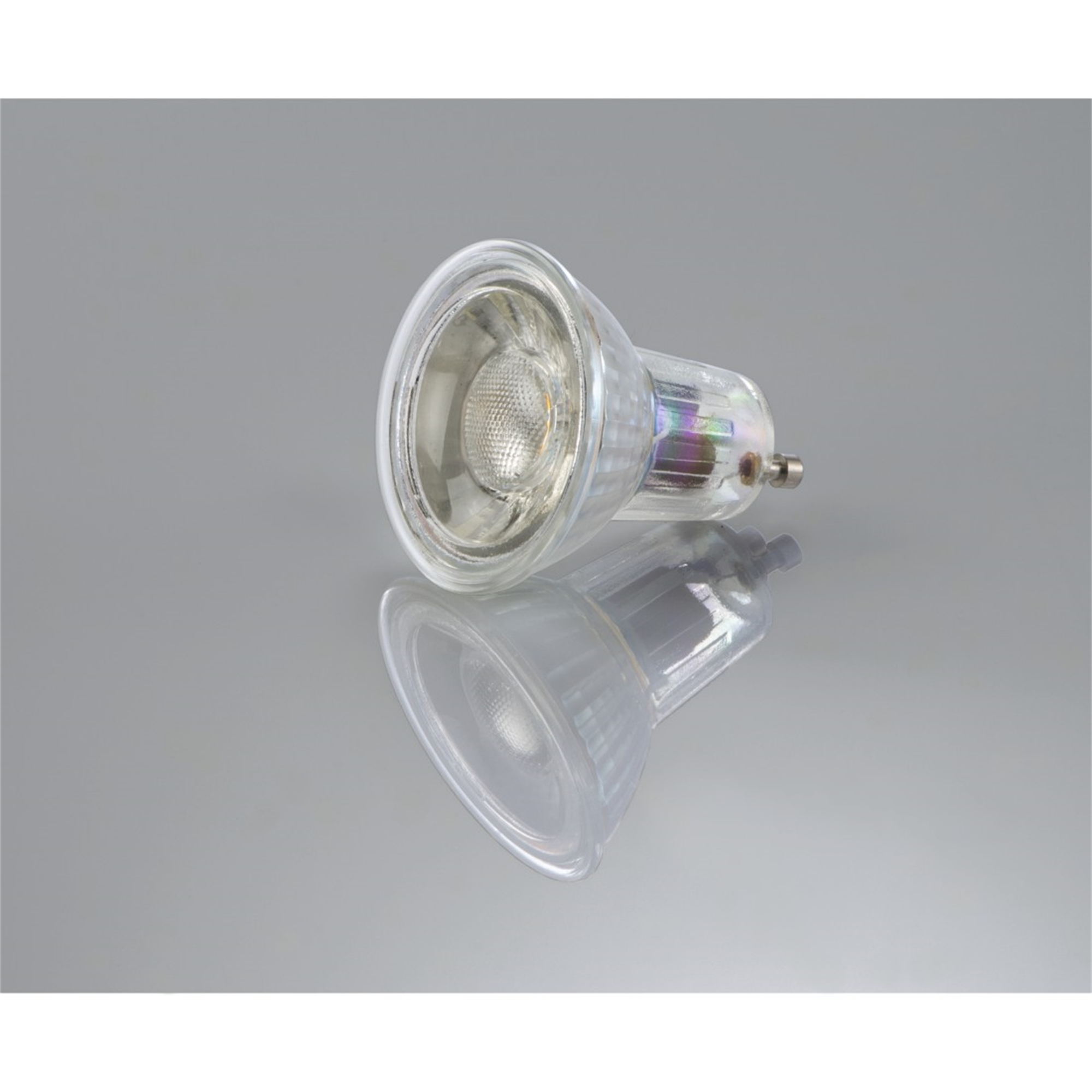 Eine Halogenlampe mit Reflexion auf einer reflektierenden Oberfläche. Es ist eine Glühbirne aus klarem Glas.