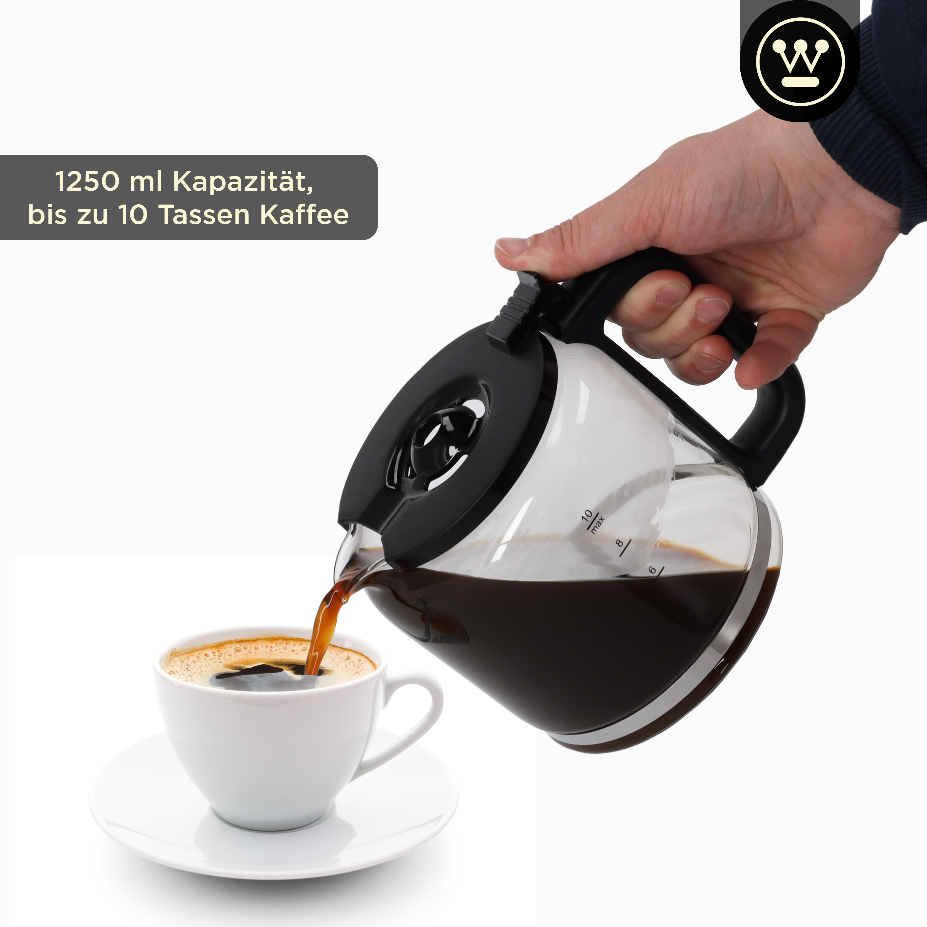 Eine Person gießt Kaffee aus einer Glaskaraffe in eine weiße Tasse auf einer weißen Untertasse.