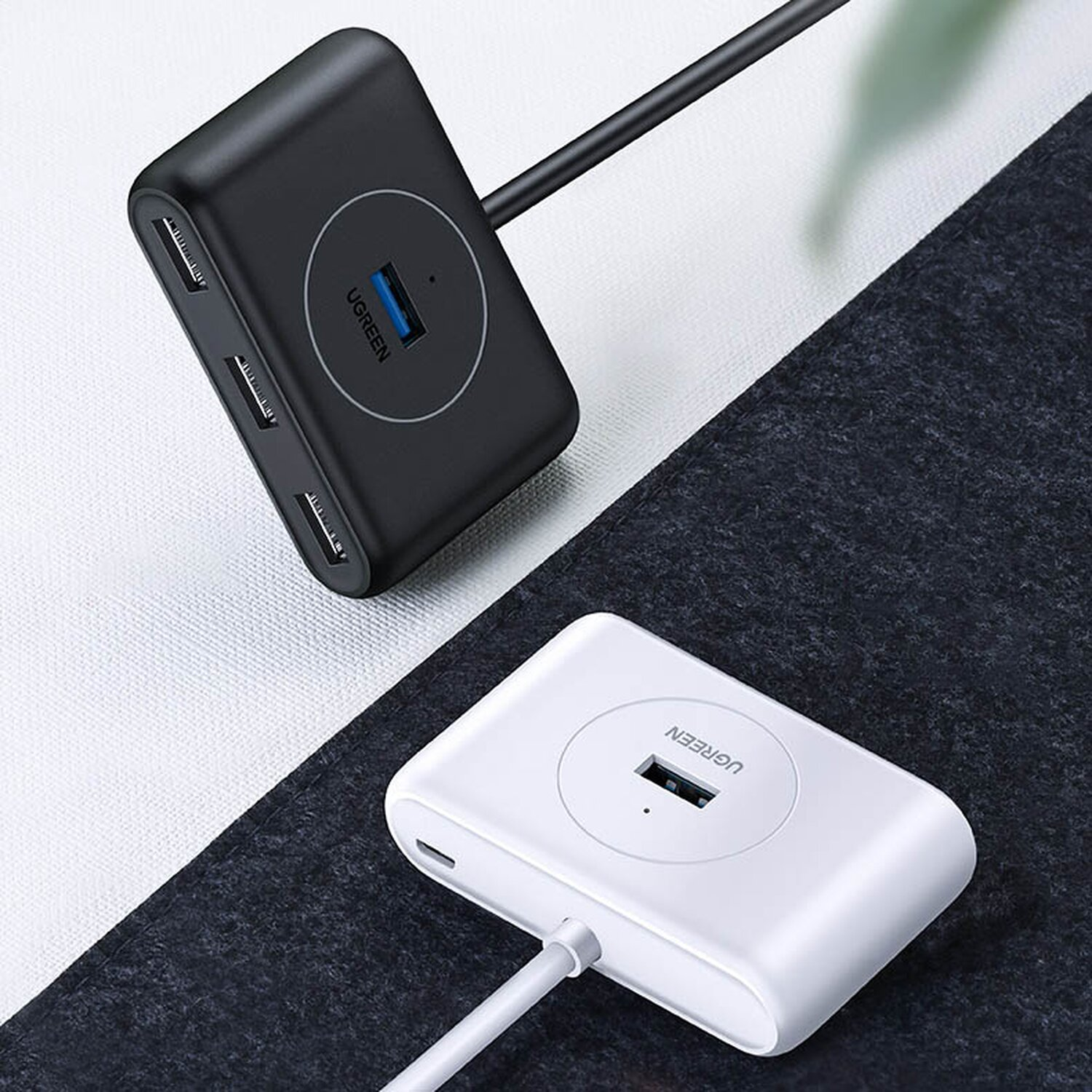 Zwei UGREEN USB-Hubs. Einer ist schwarz, einer ist weiß. Beide haben USB-Anschlüsse und ein UGREEN-Logo.
