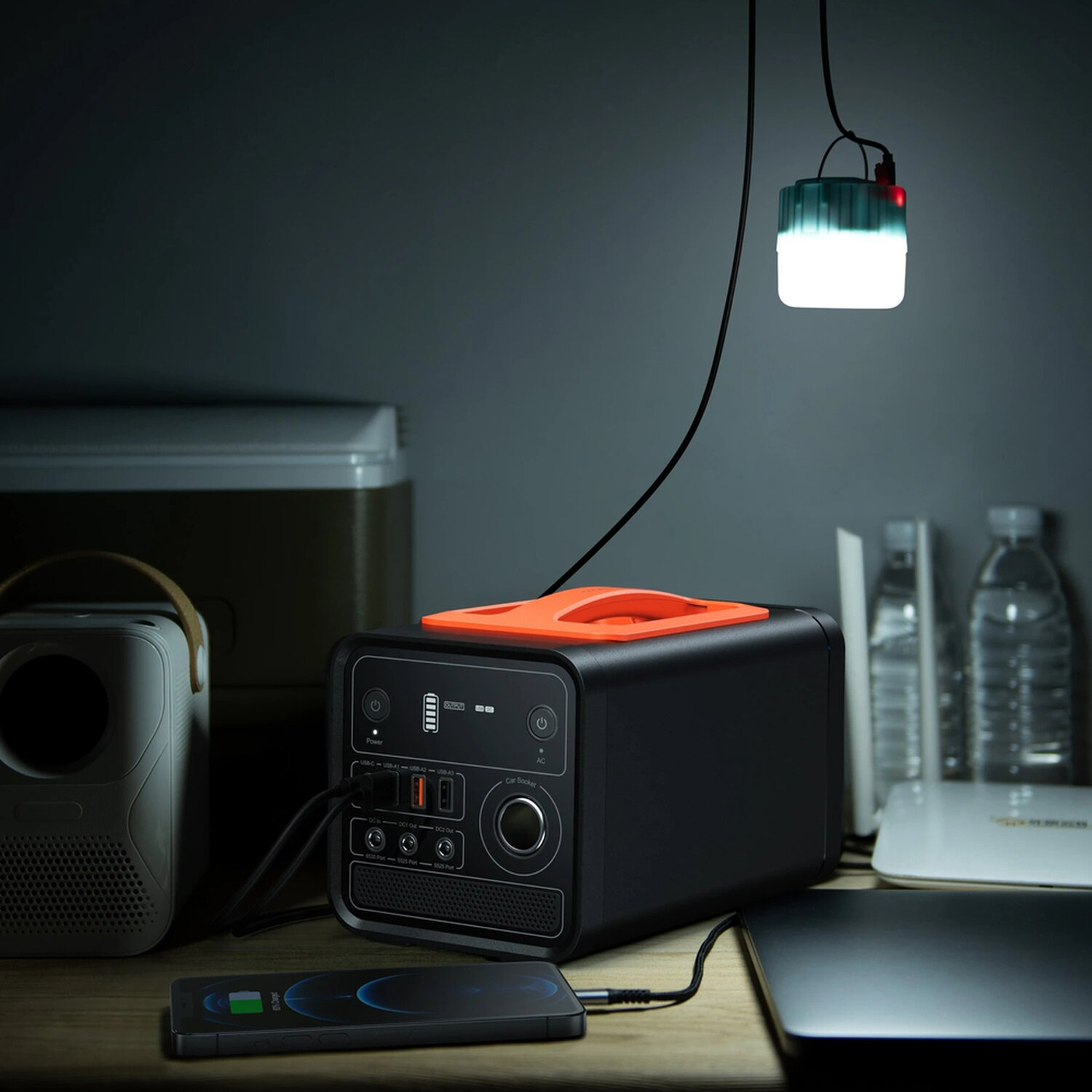 Eine schwarze tragbare Stromstation mit orangefarbenem Griff und ladendem Telefon.