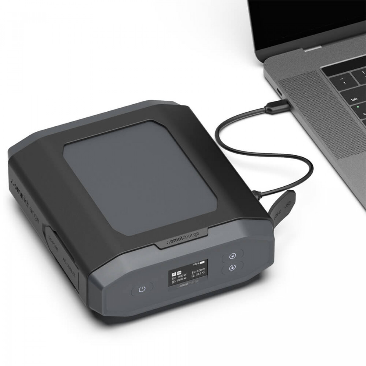 Un power bank nero e grigio collegato a un laptop con un cavo USB-C su una superficie bianca.