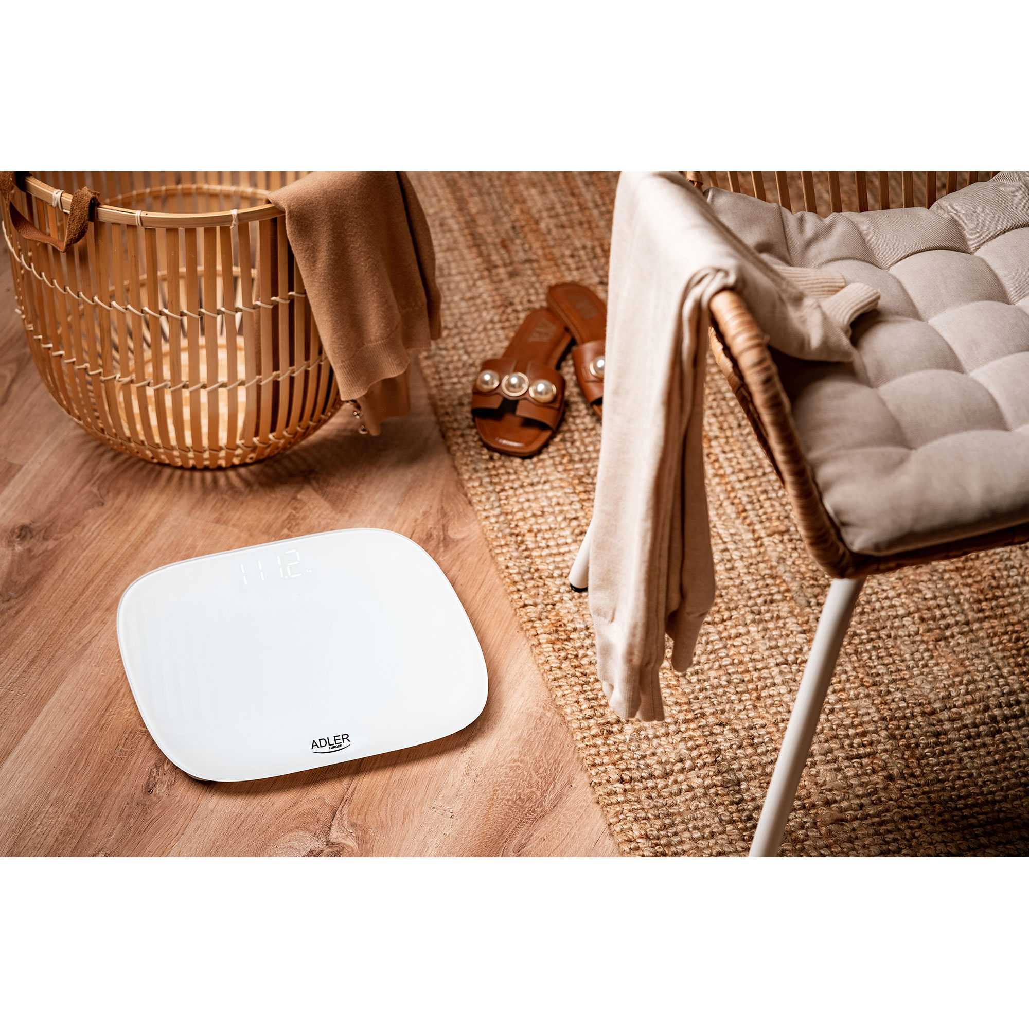 Biała waga cyfrowa na drewnianej podłodze. Ubrania i akcesoria w pobliżu.