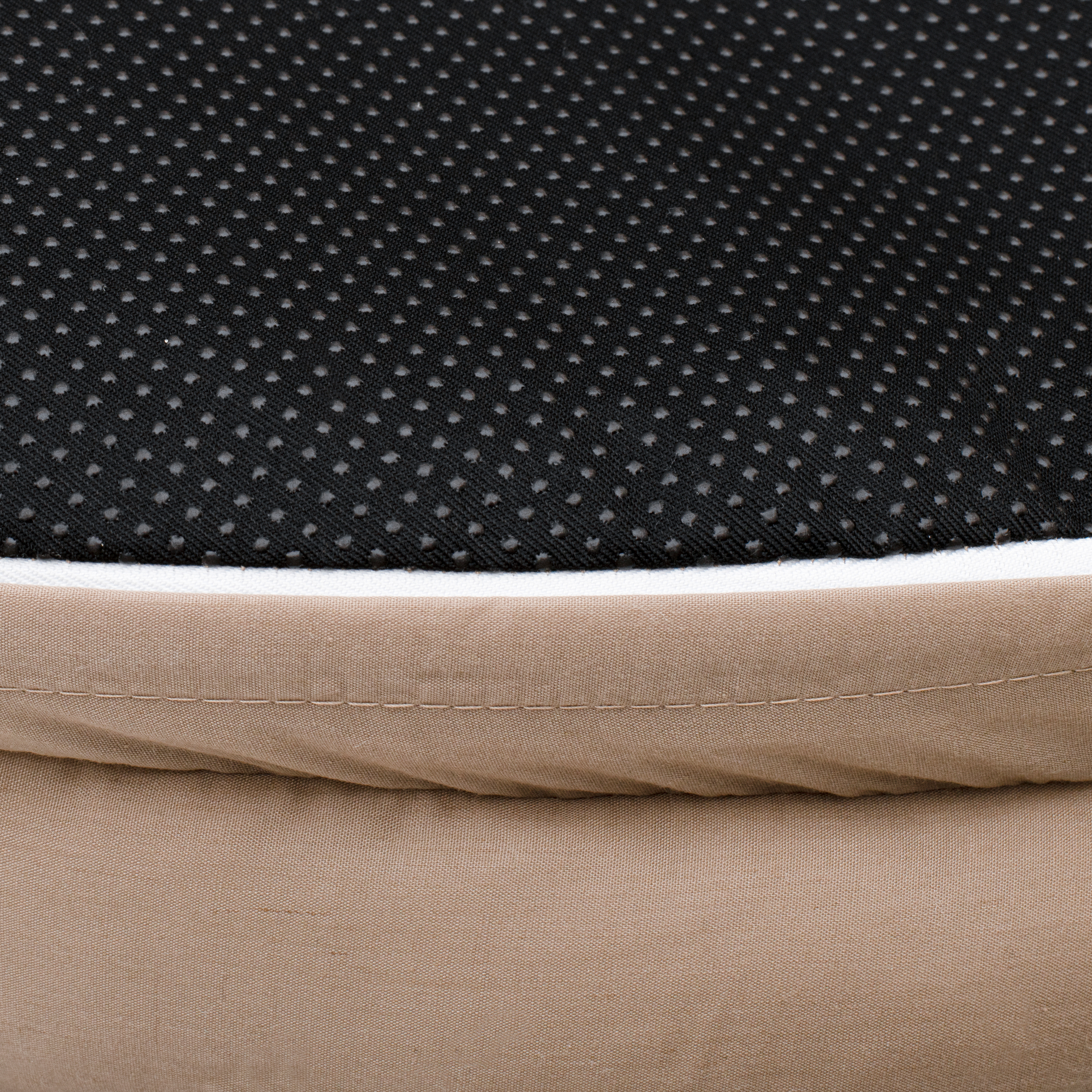 Primer plano de una cama. Tejido antideslizante negro punteado, borde blanco y tela beige.
