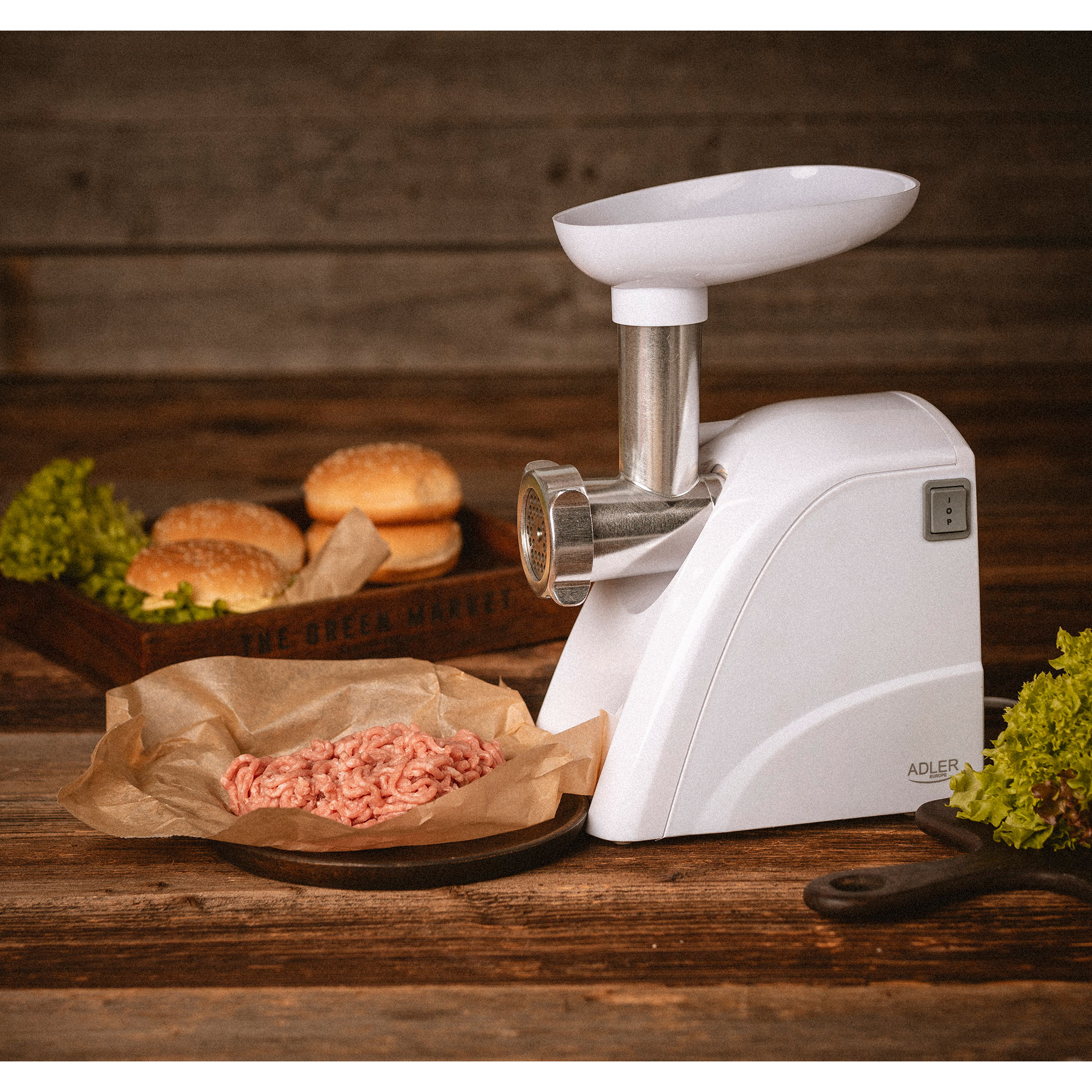 Biała maszynka do mielenia mięsa z mielonym mięsem na brązowym papierze. Bułki do burgerów z tyłu.
