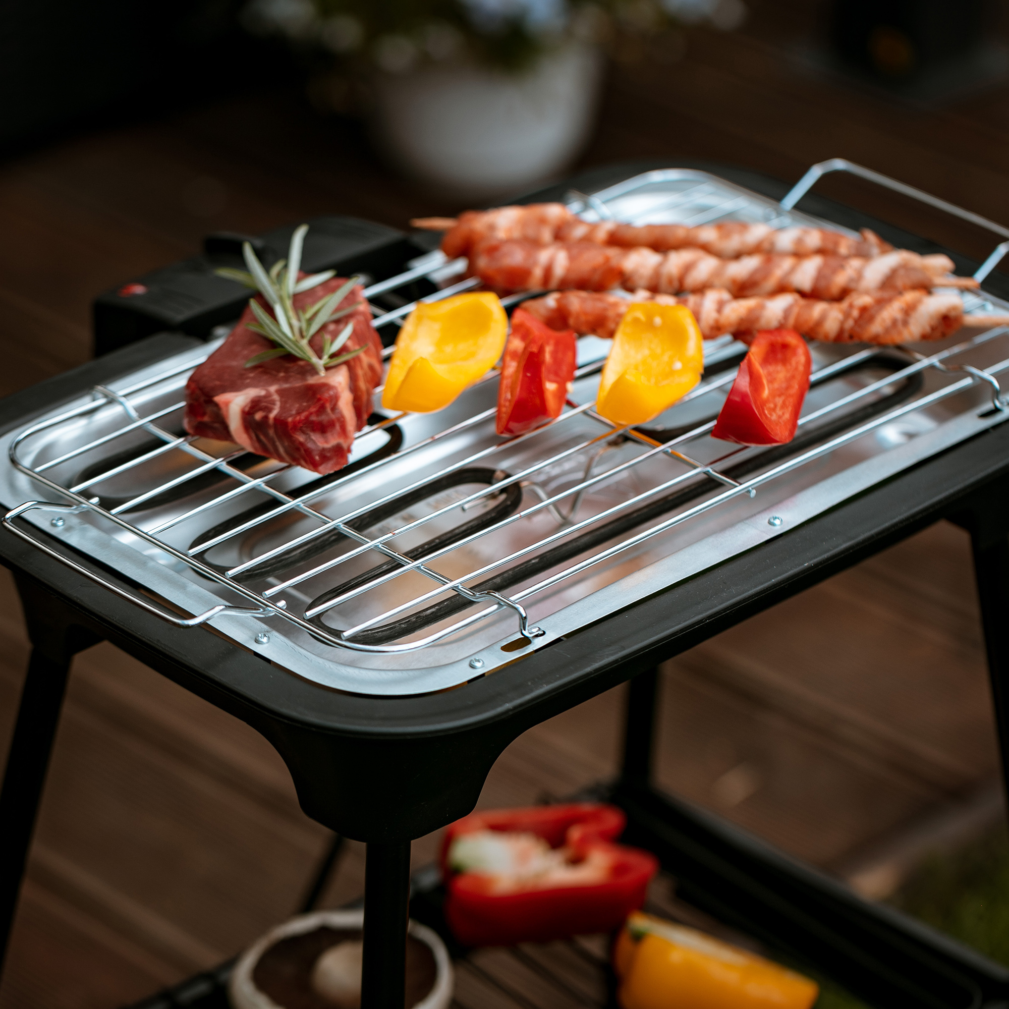 Ein Grill mit rohem Fleisch und Gemüse, bereit zum Kochen.