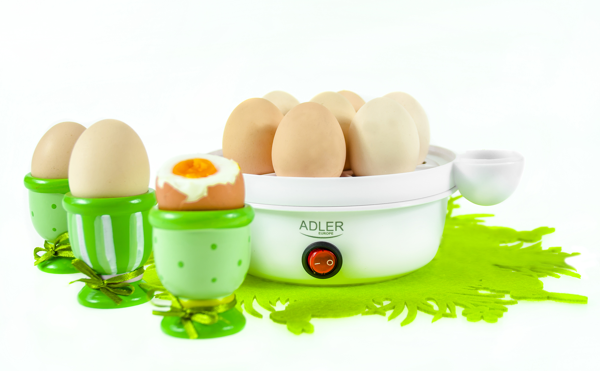 Hervidor de huevos con huevos y hueveras sobre una alfombra verde.