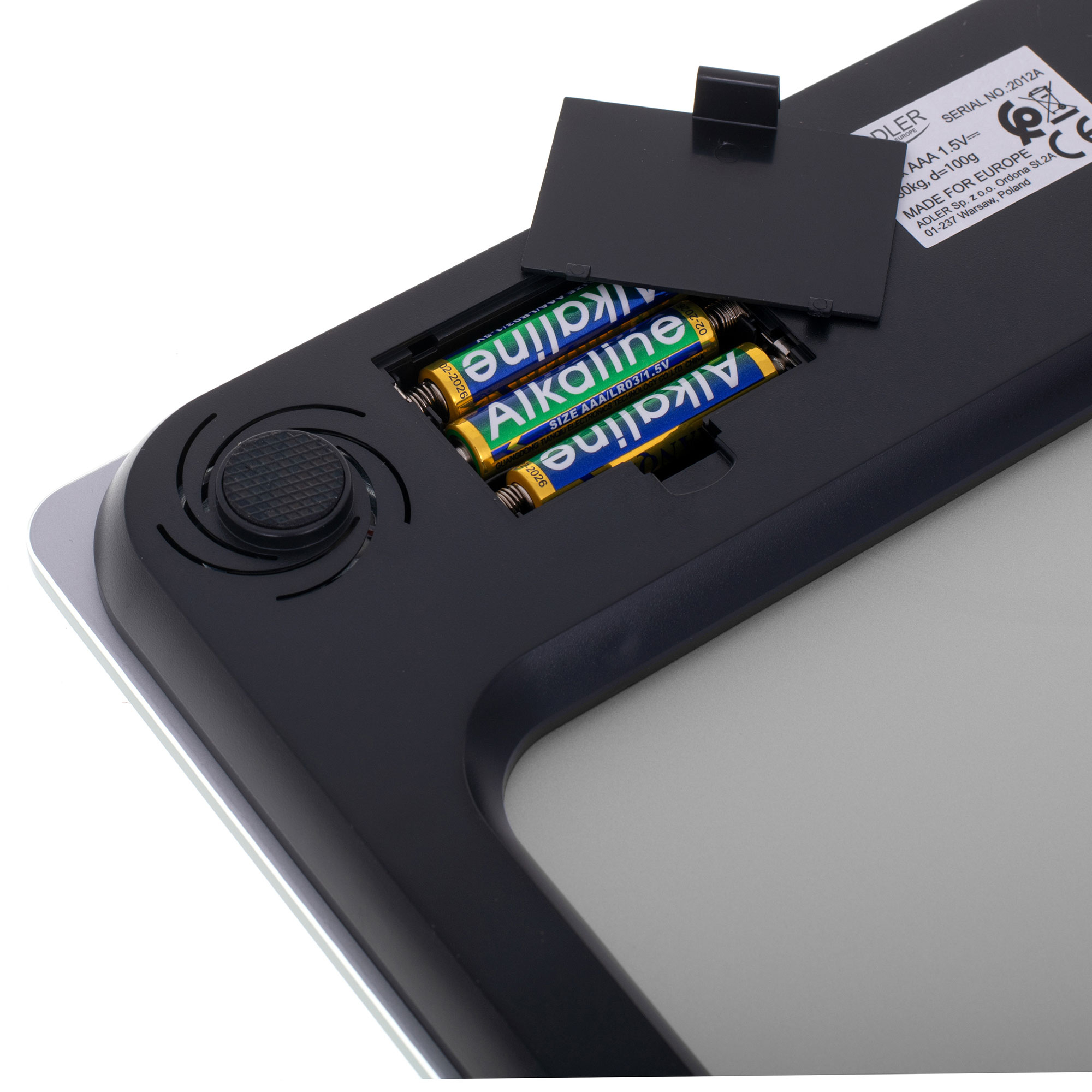 Waga elektroniczna z widocznymi bateriami. Tylna pokrywa jest otwarta, pokazując komorę baterii.