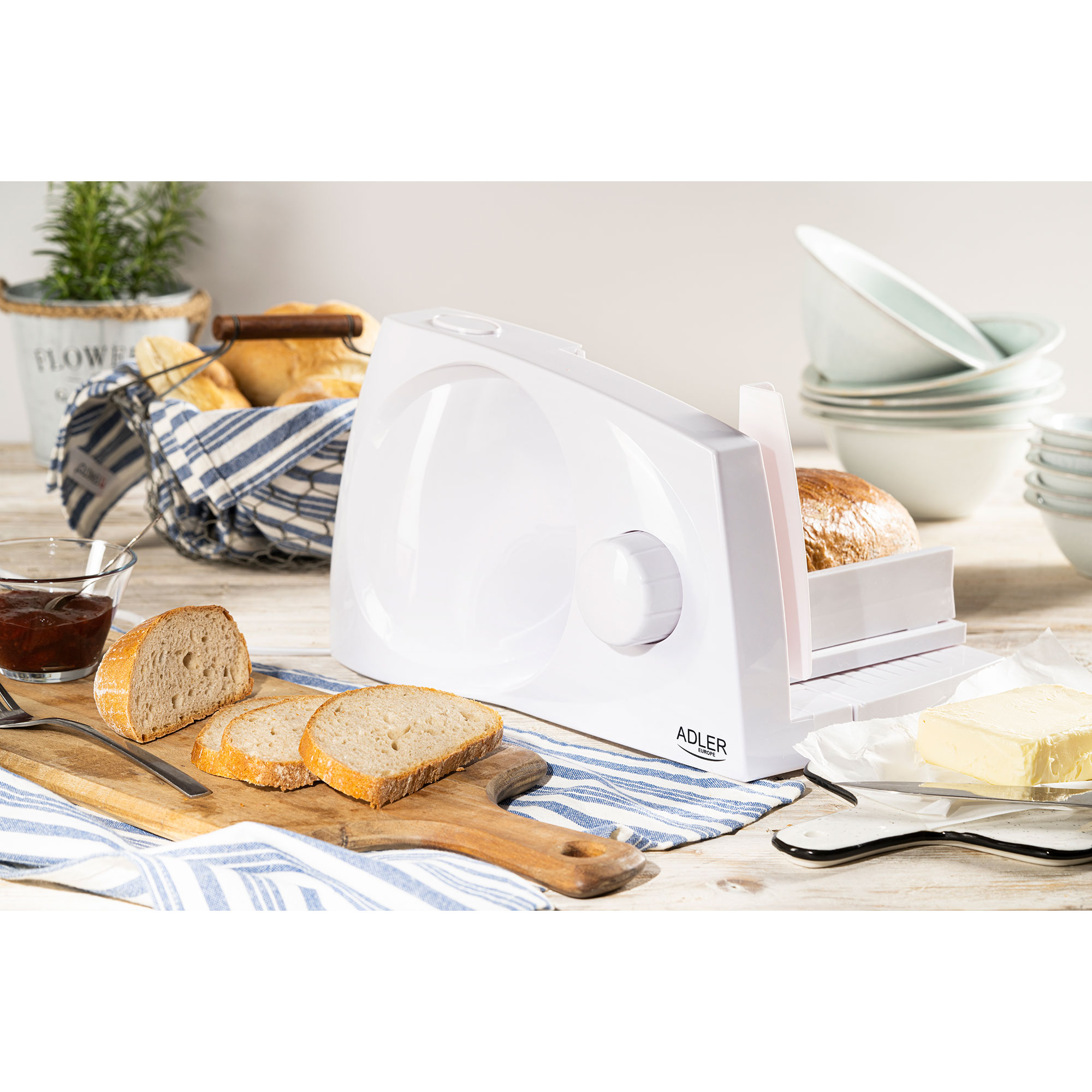Krajarka do chleba z chlebem i masłem. Drewniana deska. Białe tło.
