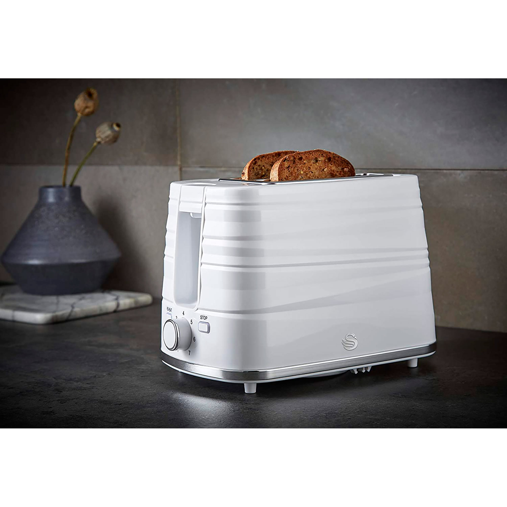 A white toaster with bread slices inside, on a dark surface, with a grey background.