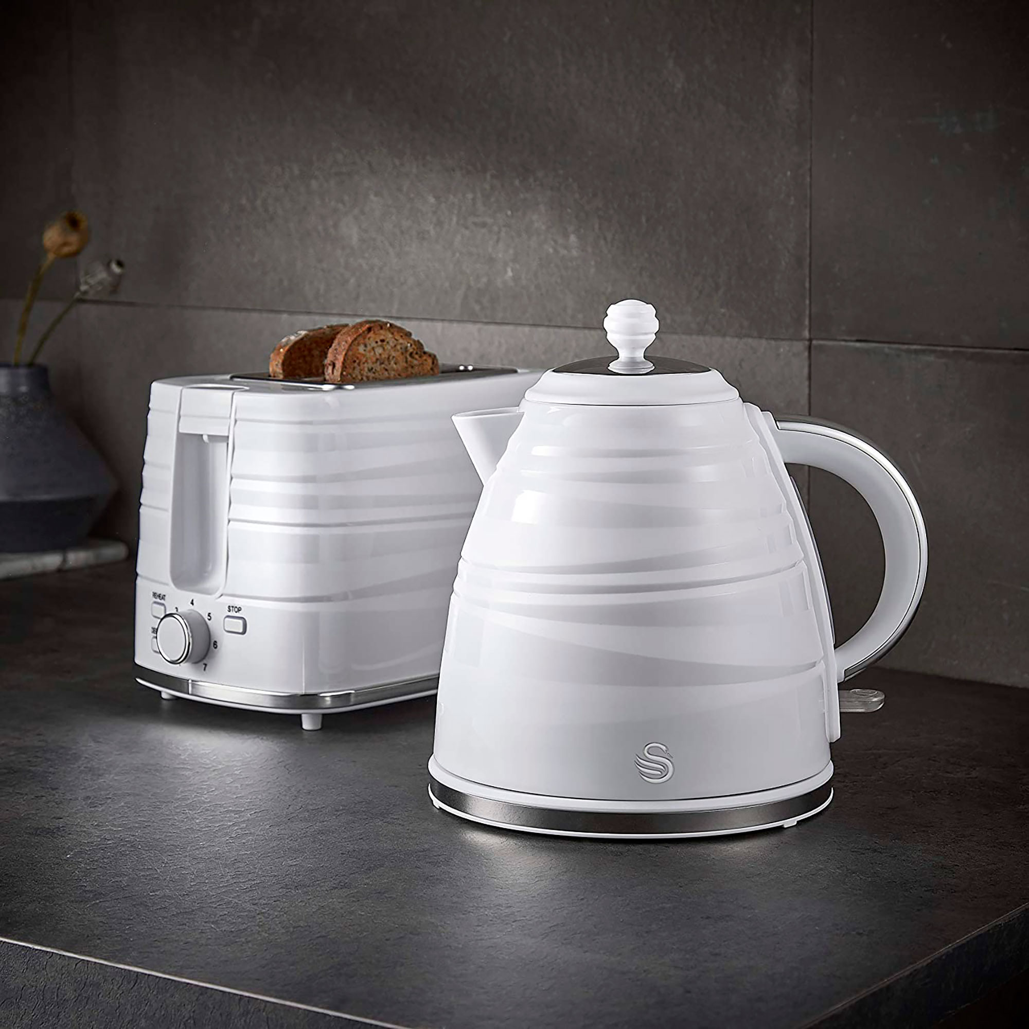 White kitchen appliance set: kettle and toaster, on a dark counter.