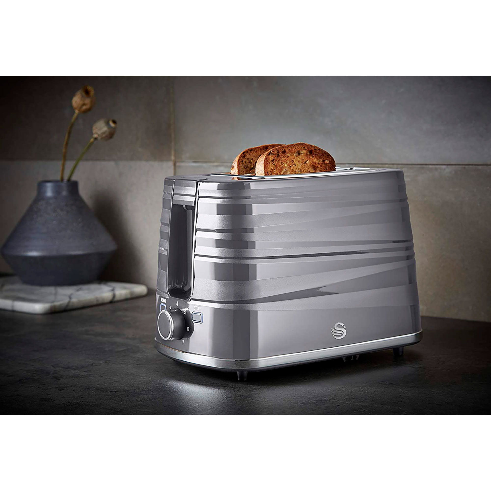 Gray toaster with two slices of toasted bread in it. It's on a black countertop with a vase.