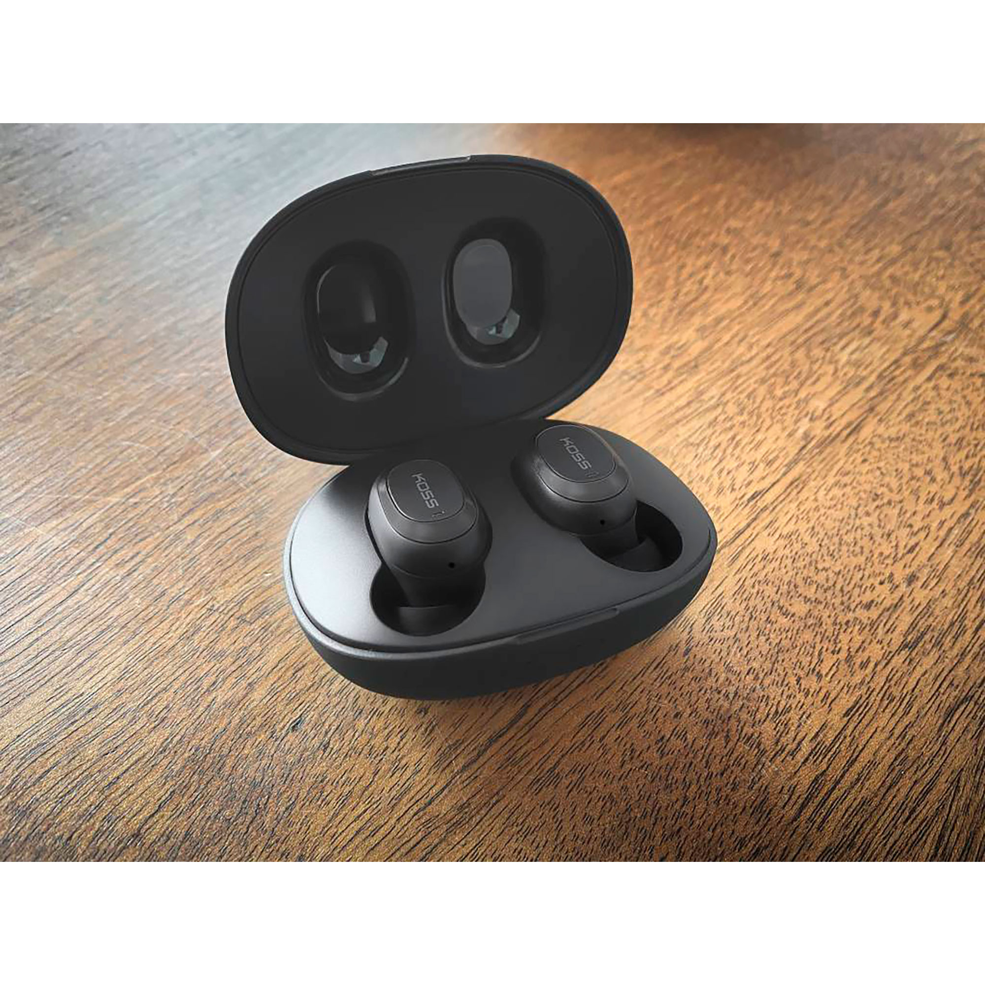 Auricolari neri in un astuccio di ricarica. Custodia aperta, mostra gli auricolari su un tavolo di legno.