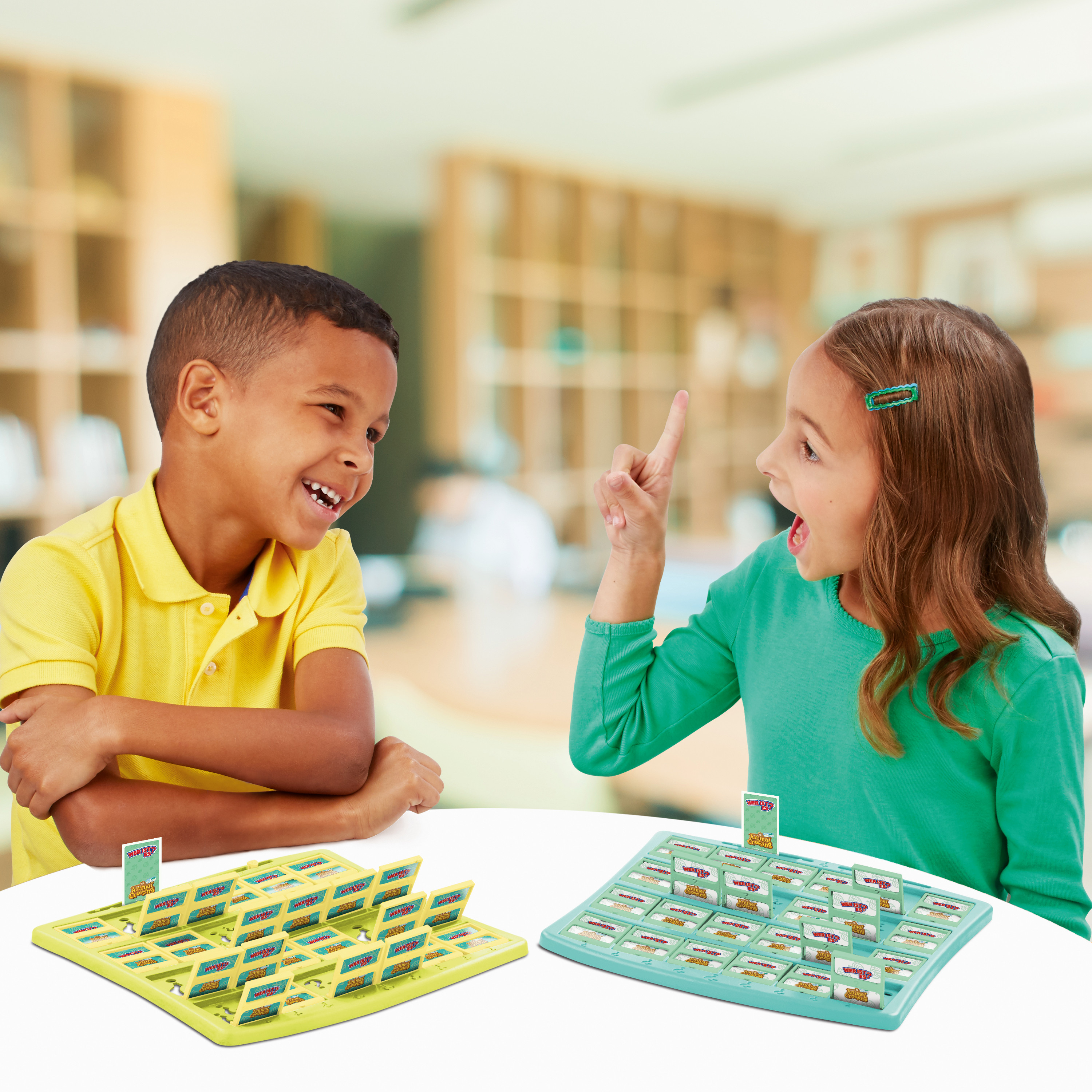 Zwei Kinder spielen ein Brettspiel. Einer zeigt, während der andere lacht. Die Spielbretter sind sichtbar.