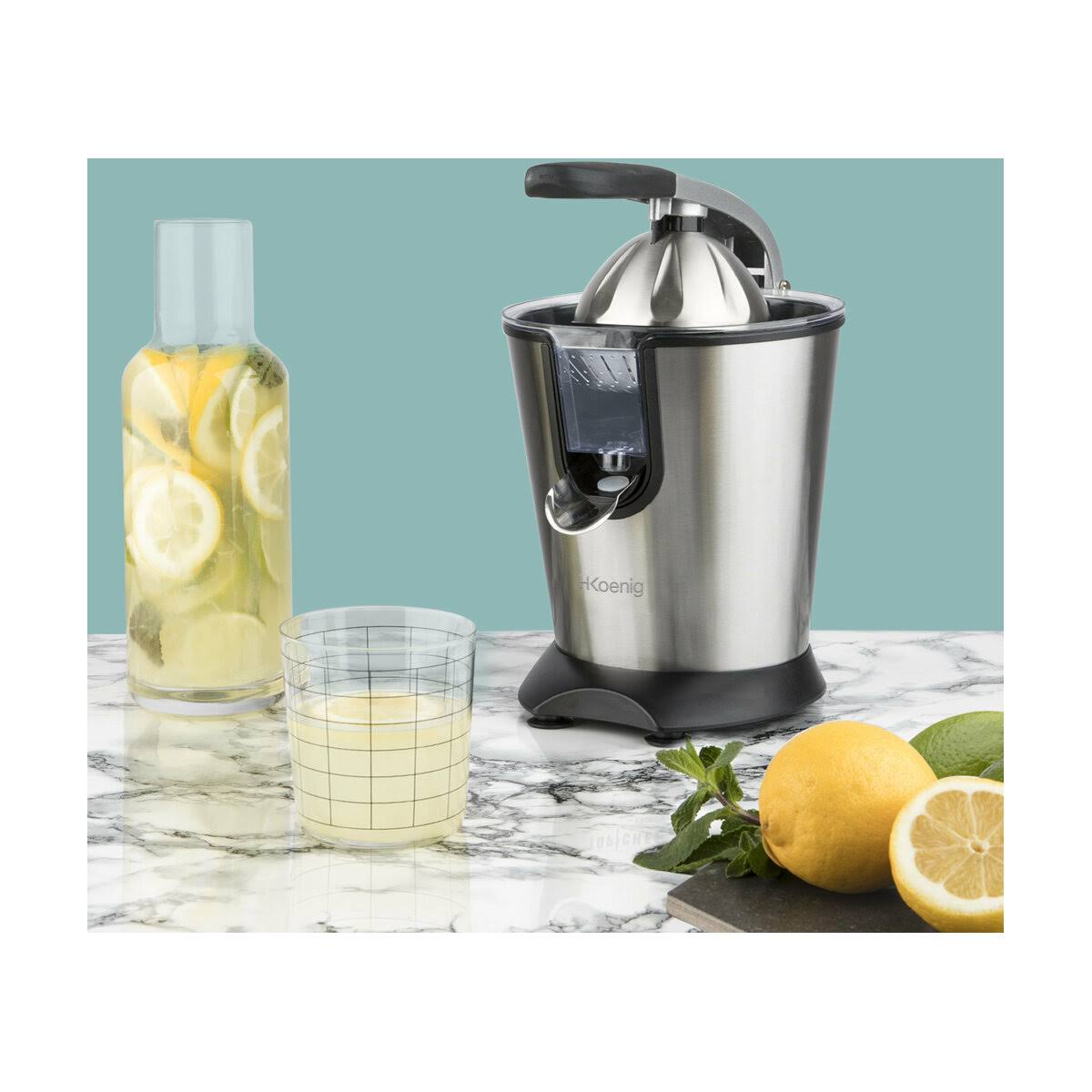 Wyiskarka z cytrynami, szklanka soku i butelka lemoniady na marmurowej powierzchni.