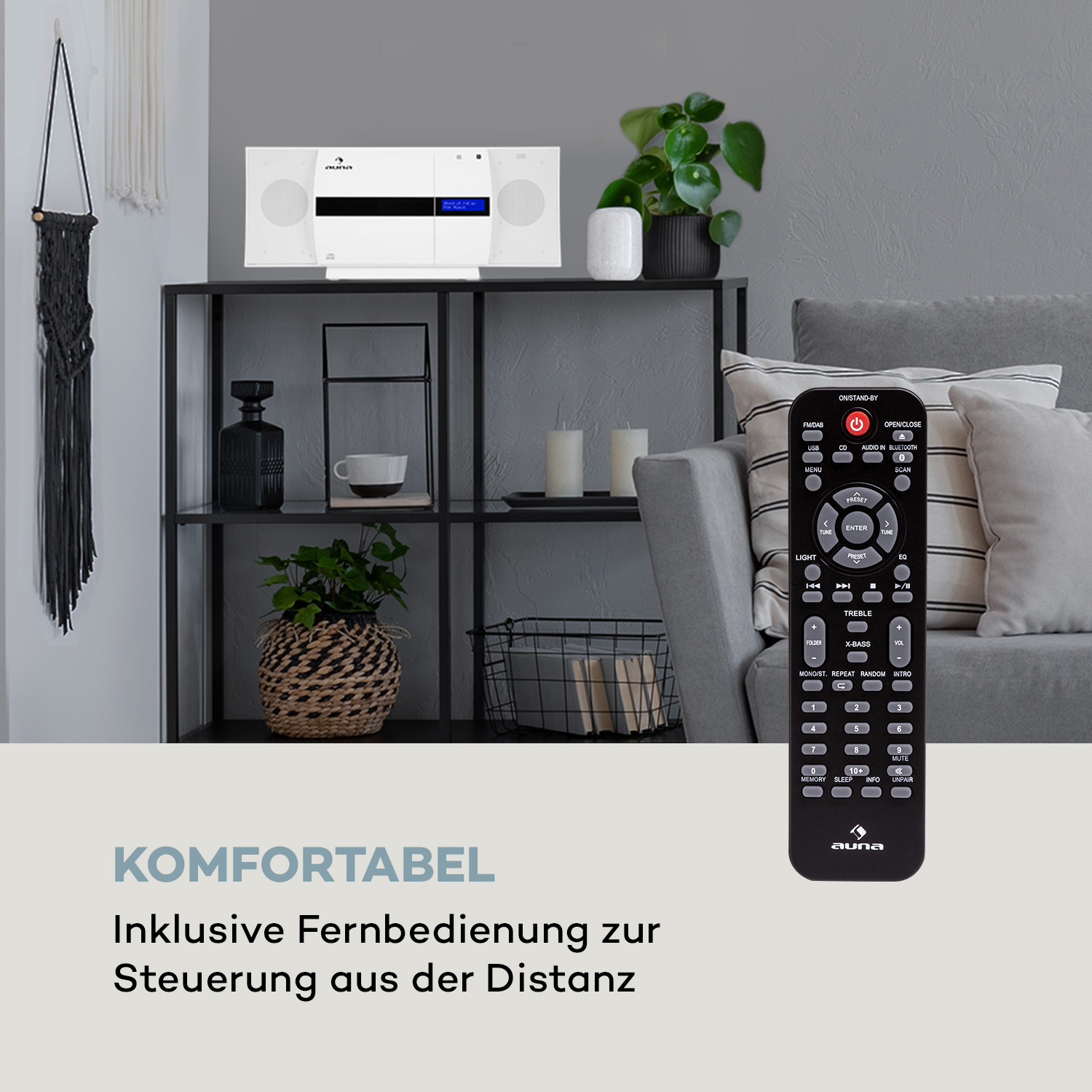 Eine schwarze Fernbedienung und eine Stereoanlage mit Pflanzen und Kerzen auf einem schwarzen Regal vor einer grauen Wand.