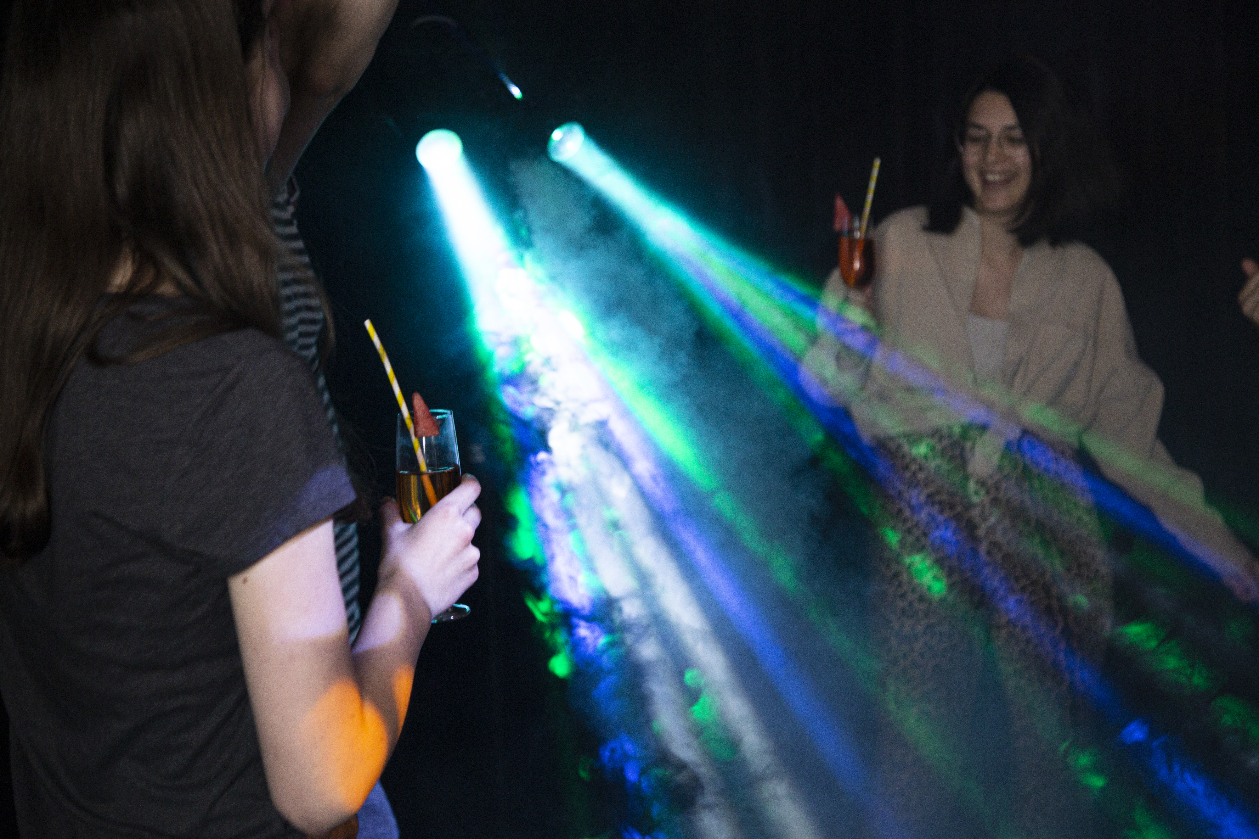 Menschen tanzen in einem Club mit bunten Lichtern.