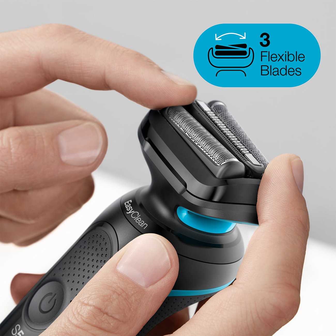 Zbliżenie czarnej golarki elektrycznej trzymanej przez dwie ręce. Golarka ma 3 ostrza.